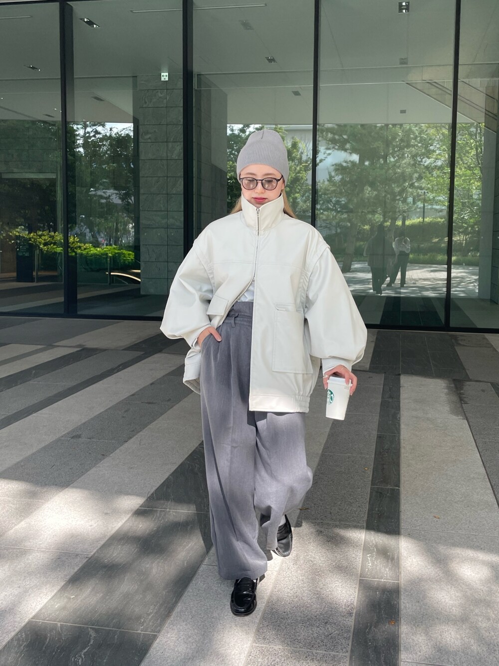 ホワイト系のジャケット/アウター、ホワイト系のTシャツ/カットソー、グレー系のスラックスを着用したレディースの秋コーディネートの4枚目の写真
