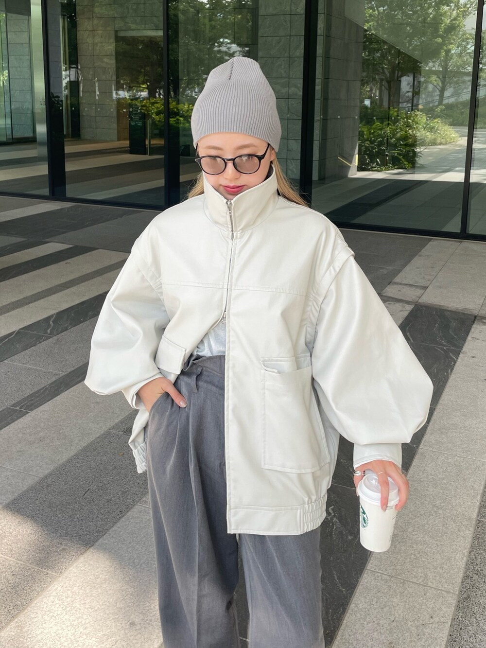 ホワイト系のジャケット/アウター、ホワイト系のTシャツ/カットソー、グレー系のスラックスを着用したレディースの秋コーディネートの5枚目の写真