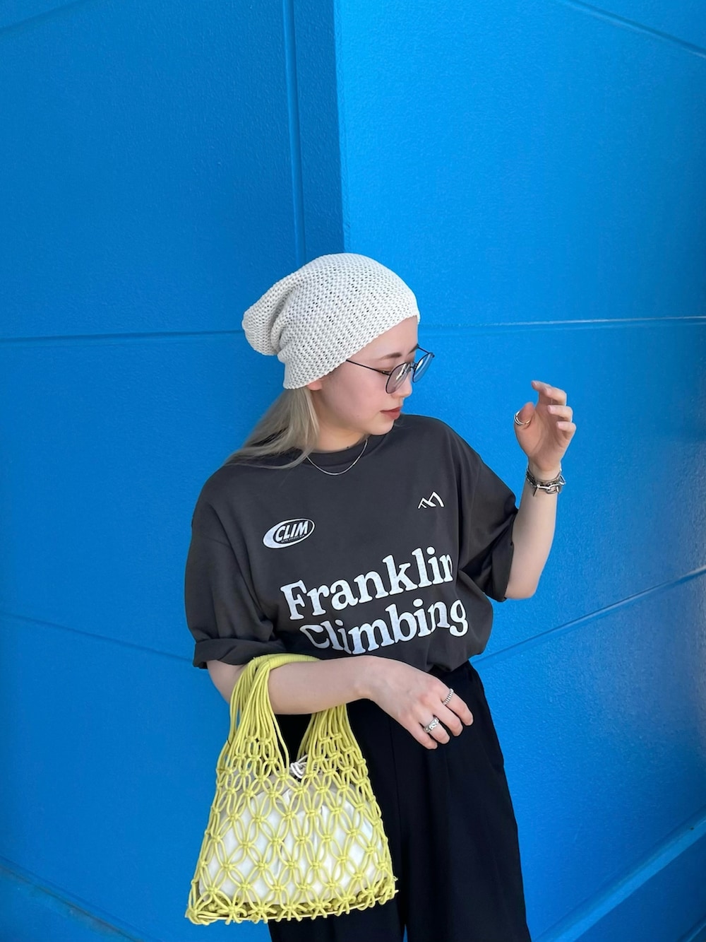 グレー系のTシャツ/カットソー、イエロー系のバッグ、ホワイト系のニットキャップ/ビーニーを着用したレディースの夏コーディネートの2枚目の写真