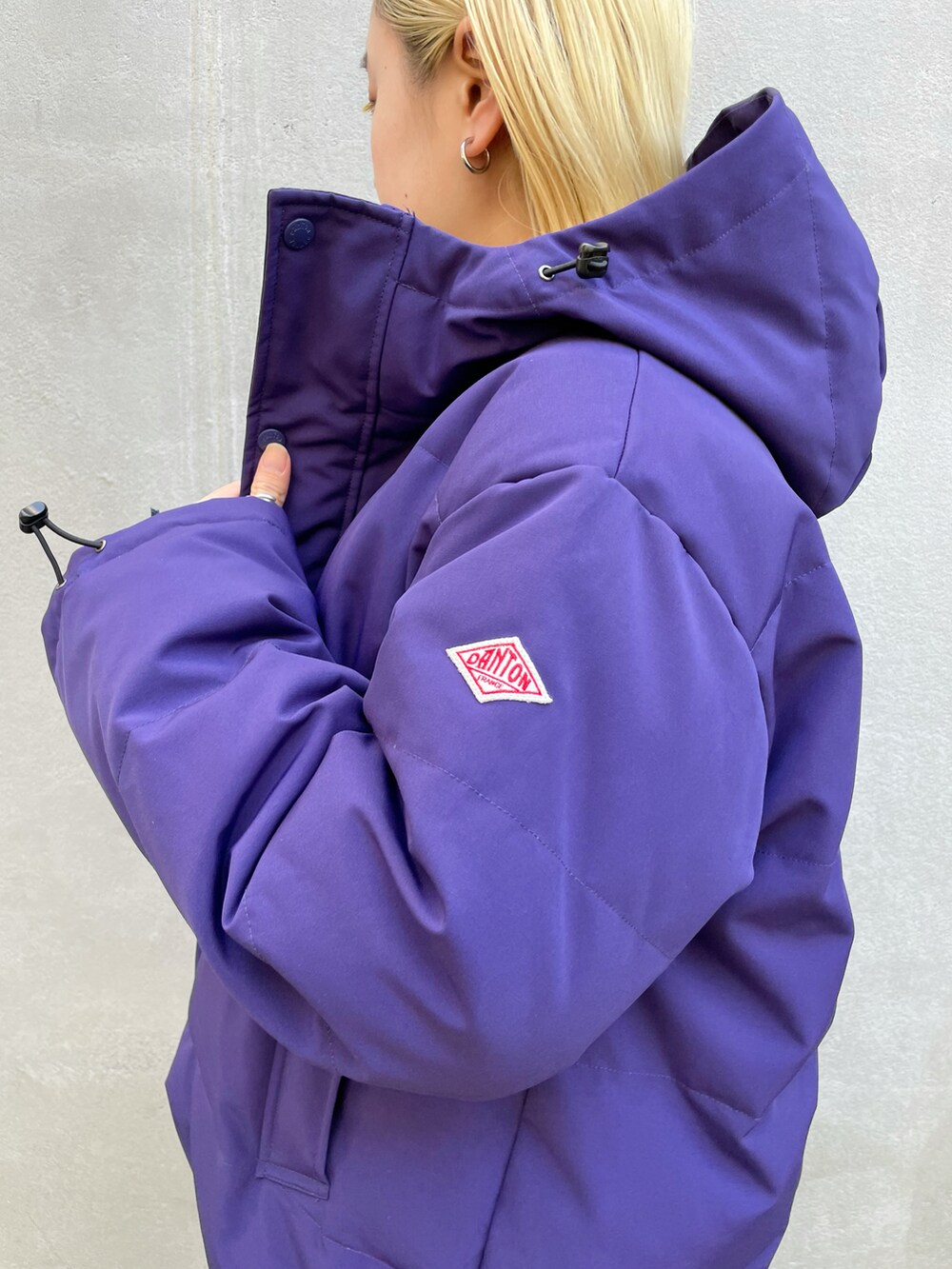 パープル系のダウンジャケット/コート、ブラック系のワンピース、ブラック系のブーツを着用したレディースの秋コーディネートの5枚目の写真