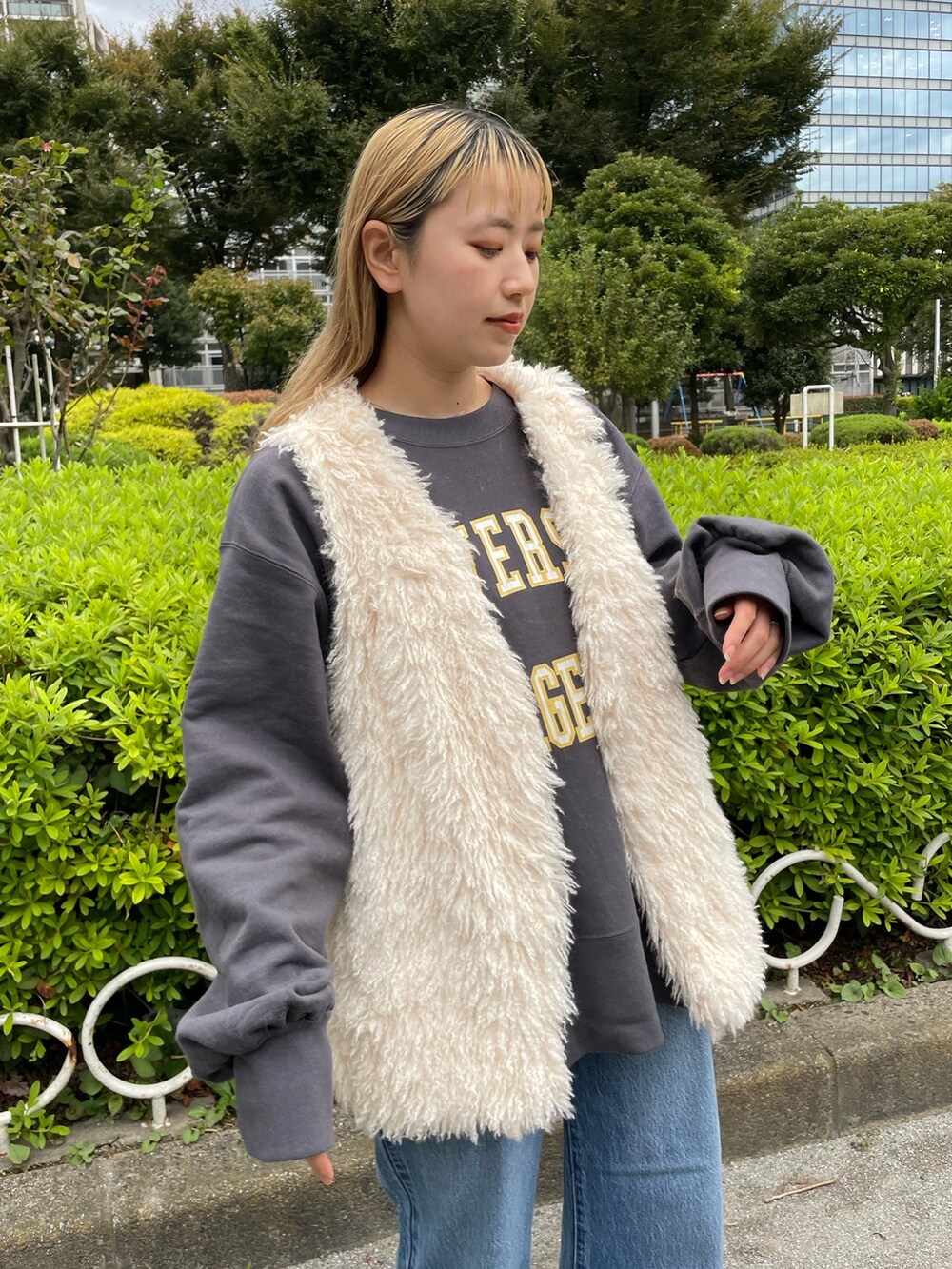 ホワイト系のベスト、グレー系のスウェット、ブルー系のデニムパンツを着用したレディースの秋コーディネートの3枚目の写真