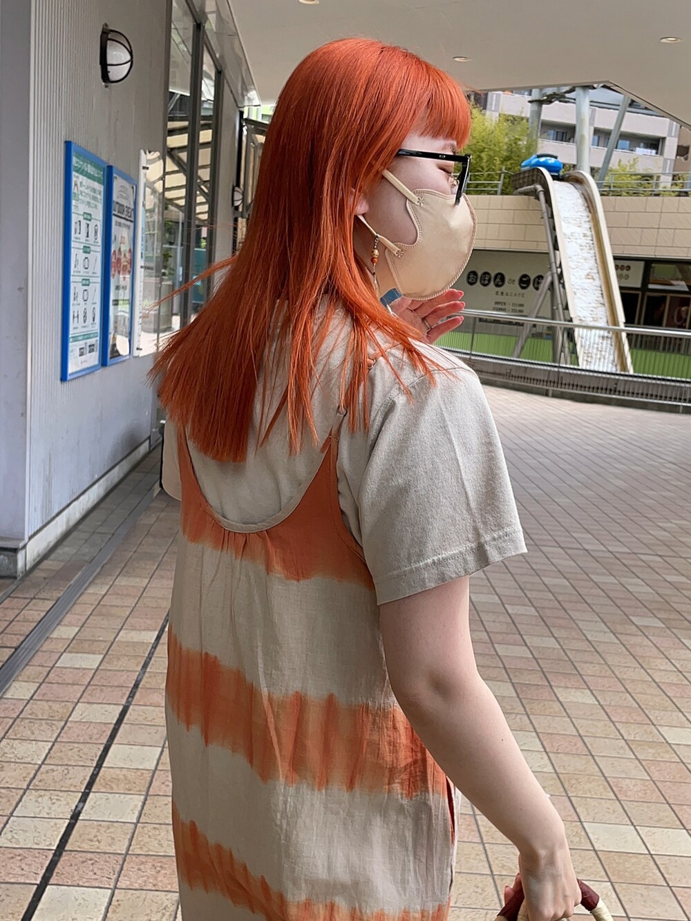 オレンジ系のワンピース、ベージュ系のTシャツ/カットソー、ブラック系のかごバッグを着用したレディースの春コーディネートの4枚目の写真