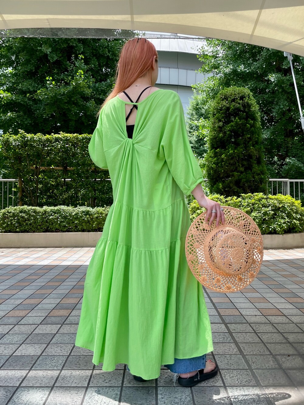 グリーン系のワンピース、ブルー系のデニムパンツ、ベージュ系のトートバッグを着用したレディースの夏コーディネートの2枚目の写真