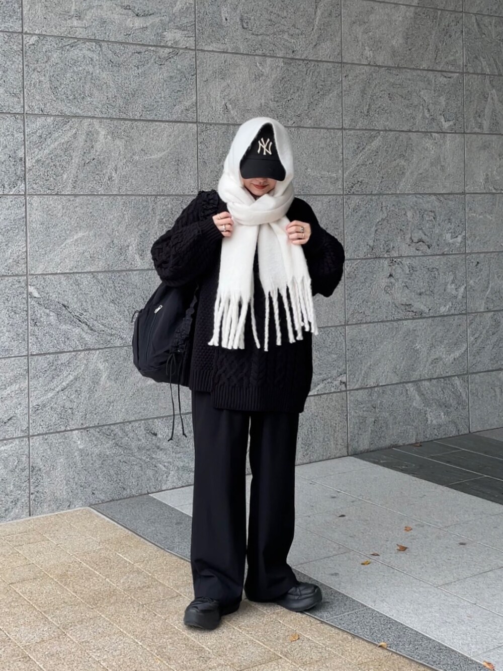 ブラック系のショルダーバッグ、ブラック系のニット/セーター、ホワイト系のマフラーを着用したレディースの冬コーディネートの7枚目の写真