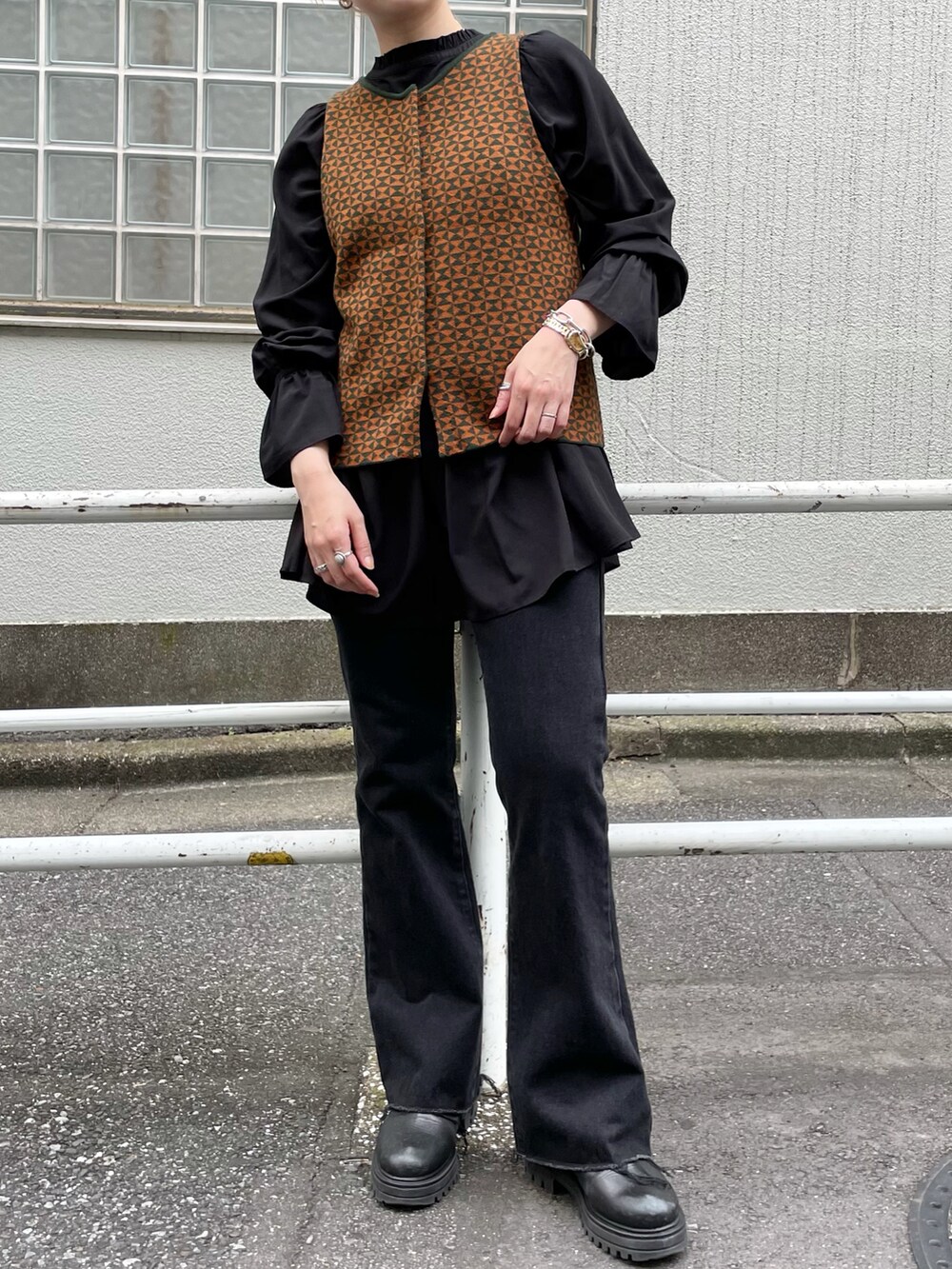 グリーン系のステンカラーコート、ブラウン系のベスト、ブラック系のシャツ/ブラウスを着用したレディースの秋コーディネートの4枚目の写真