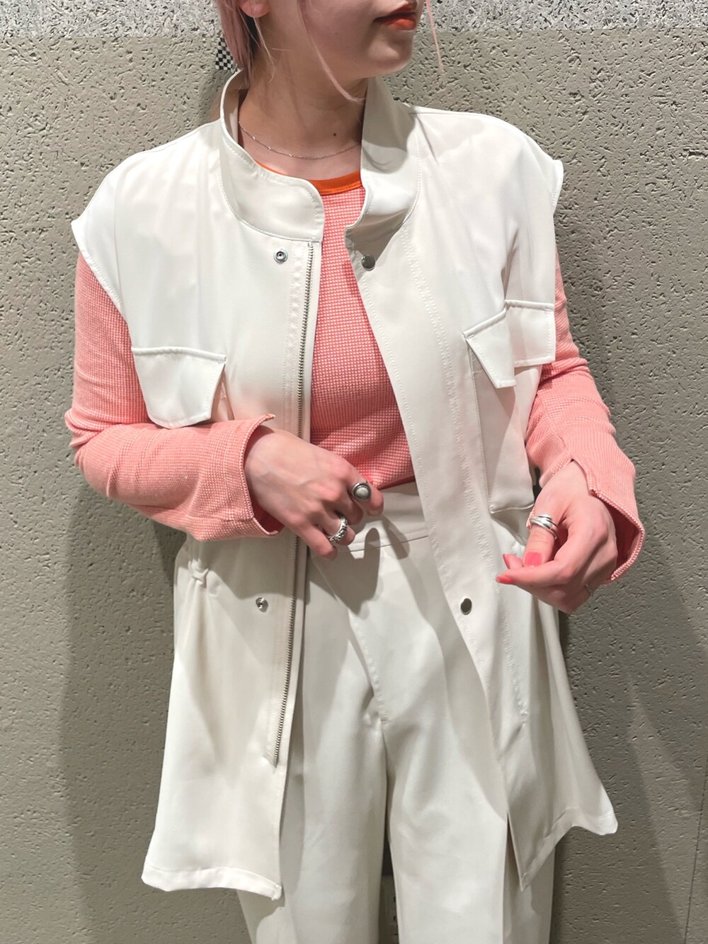 ホワイト系のベスト、オレンジ系のTシャツ/カットソー、ホワイト系のスラックスを着用したレディースの春コーディネートの2枚目の写真