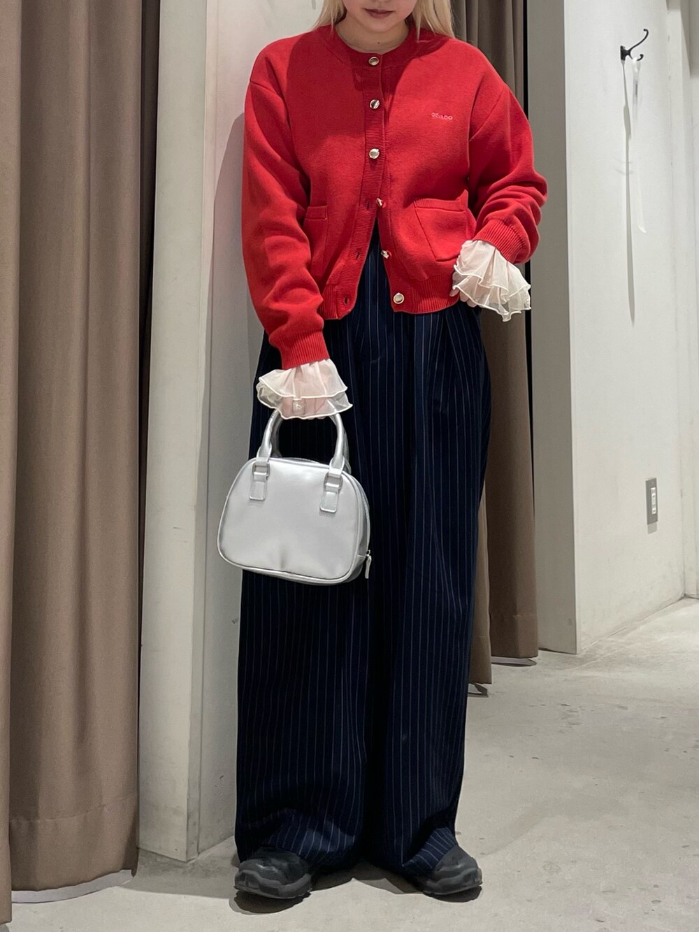 レッド系のカーディガン/ボレロ、イエロー系のTシャツ/カットソー、ブルー系のスラックスを着用したレディースの冬コーディネートの2枚目の写真