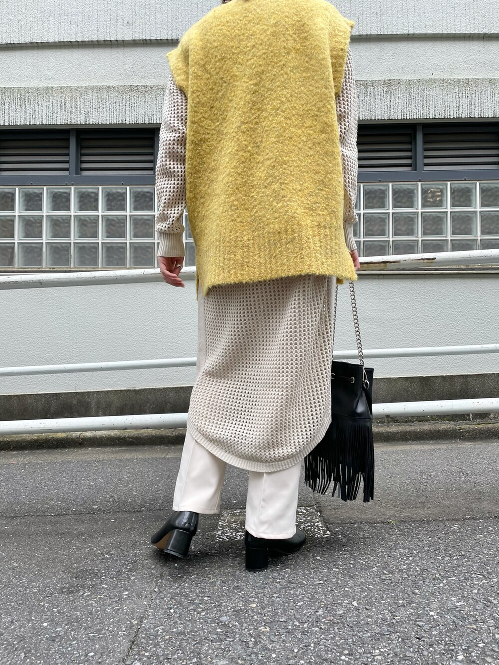 イエロー系のベスト、ブラック系のショルダーバッグ、ホワイト系のワンピースを着用したレディースの秋コーディネートの5枚目の写真