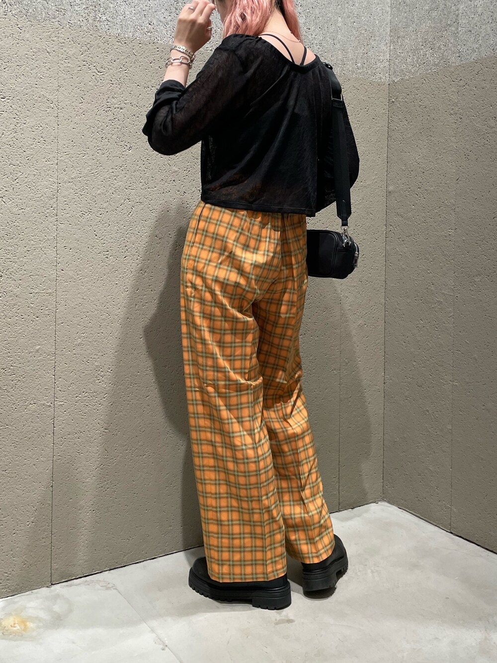 ブラック系のカーディガン/ボレロ、オレンジ系のスラックスを着用したレディースの夏コーディネートの2枚目の写真