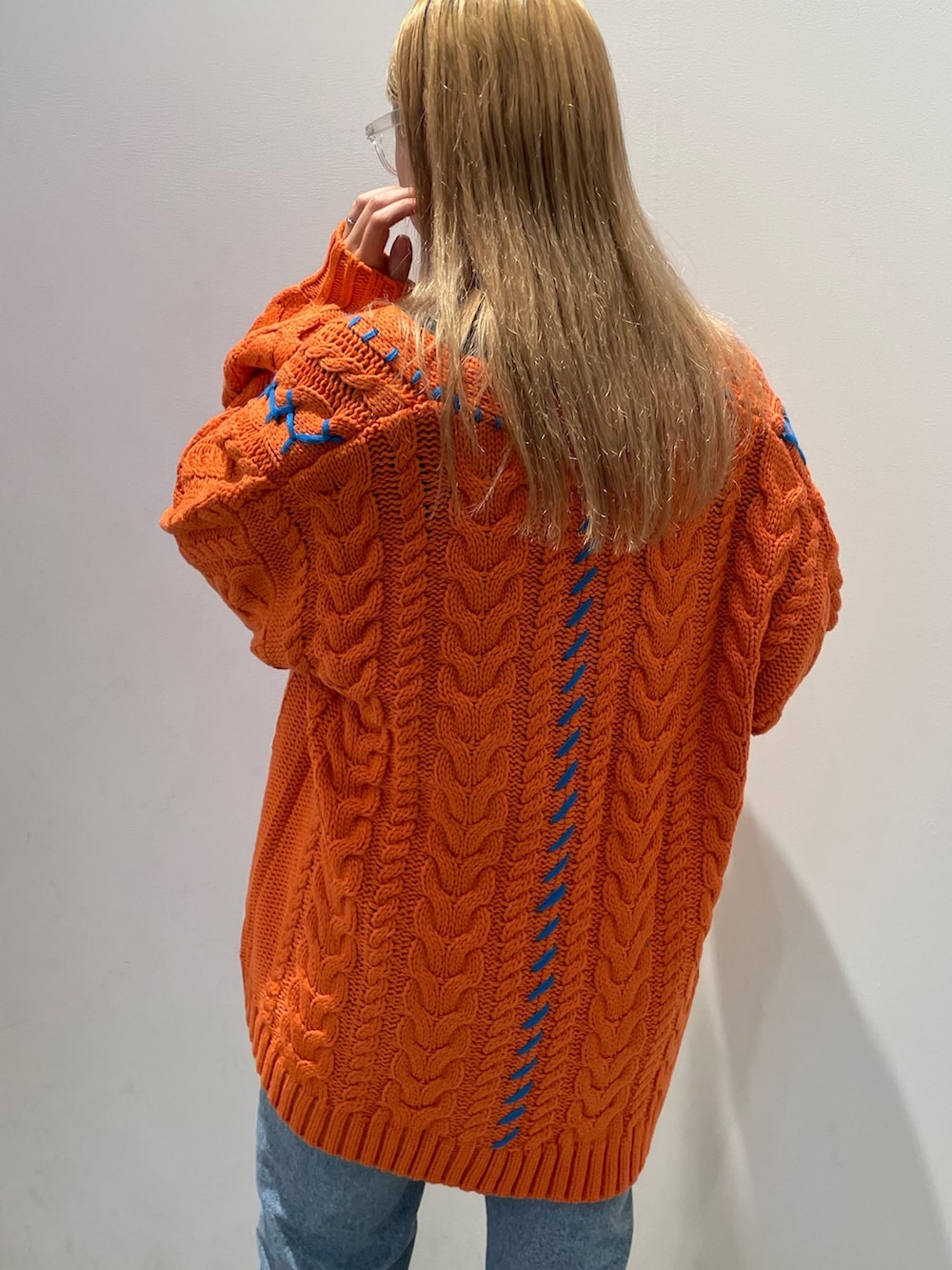 オレンジ系のカーディガン/ボレロ、ブルー系のデニムパンツ、ベージュ系のトートバッグを着用したレディースの秋コーディネートの3枚目の写真