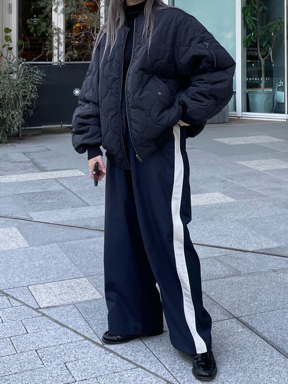 ブラック系のジャケット/アウター、ブラック系のニット/セーター、ブルー系のスラックスを着用したレディースの冬コーディネートの2枚目の写真