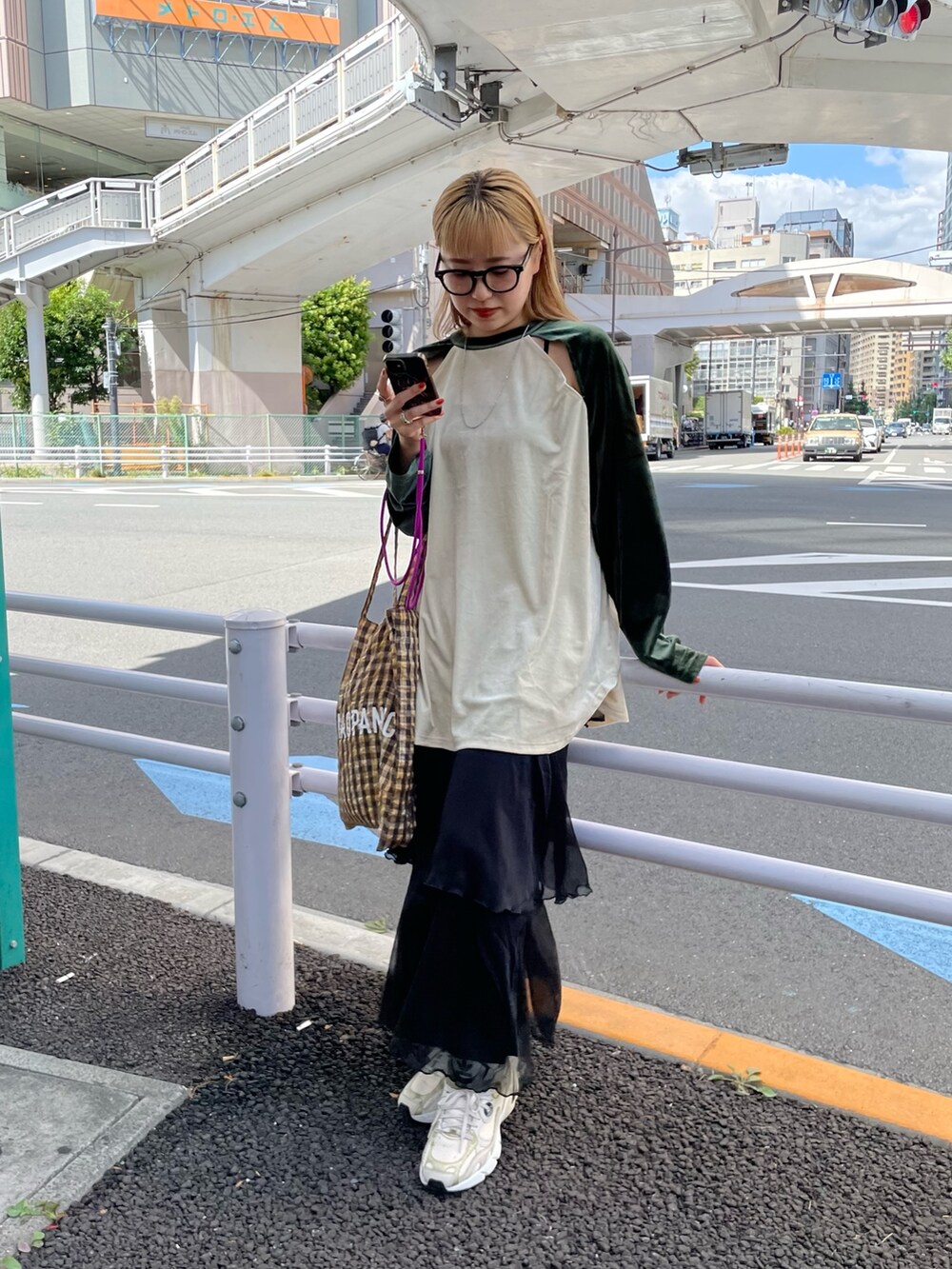 グリーン系のTシャツ/カットソー、イエロー系のトートバッグ、ブラック系のスカートを着用したレディースの秋コーディネートの2枚目の写真