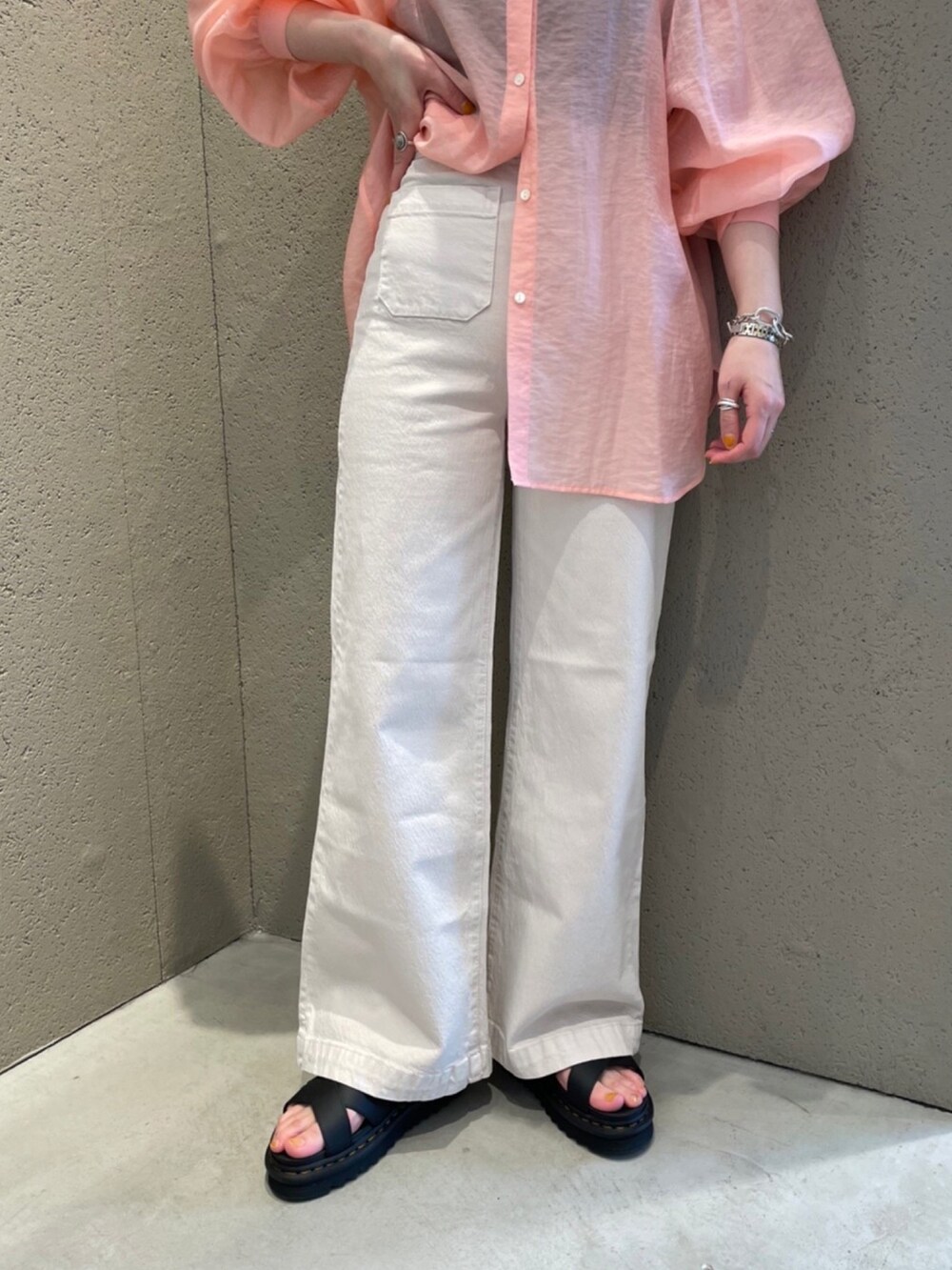 ピンク系のシャツ/ブラウス、ブラック系のサンダル、ホワイト系のデニムパンツを着用したレディースの春コーディネートの5枚目の写真