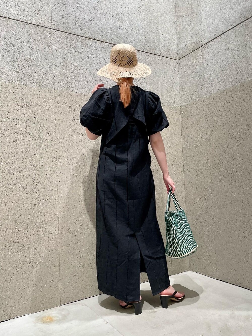 ブラック系のワンピース、グリーン系のかごバッグ、ブラック系のサンダルを着用したレディースの春コーディネートの3枚目の写真