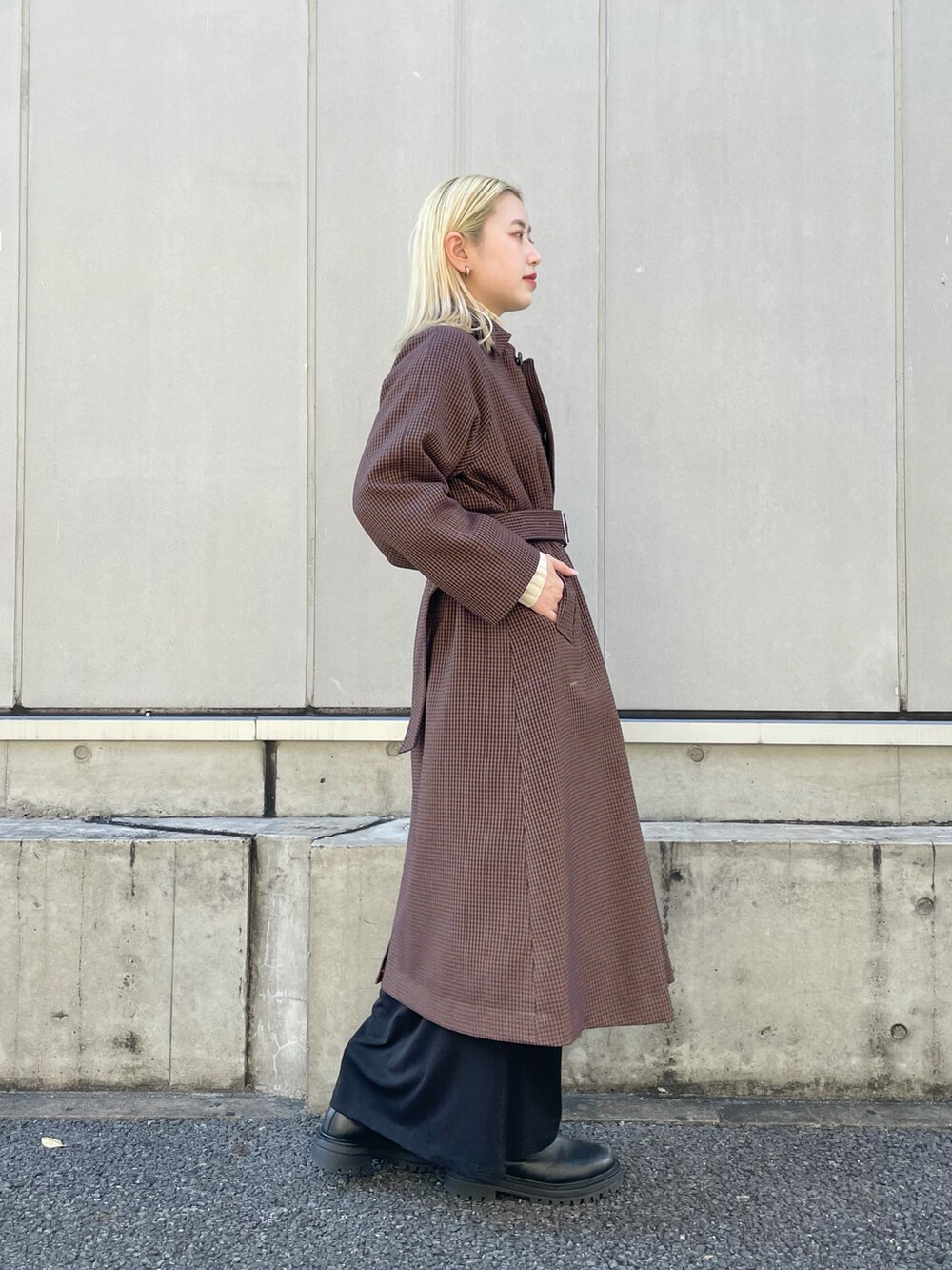 ブルー系のステンカラーコート、ホワイト系のニット/セーター、ブラック系のワンピースを着用したレディースの秋コーディネートの2枚目の写真