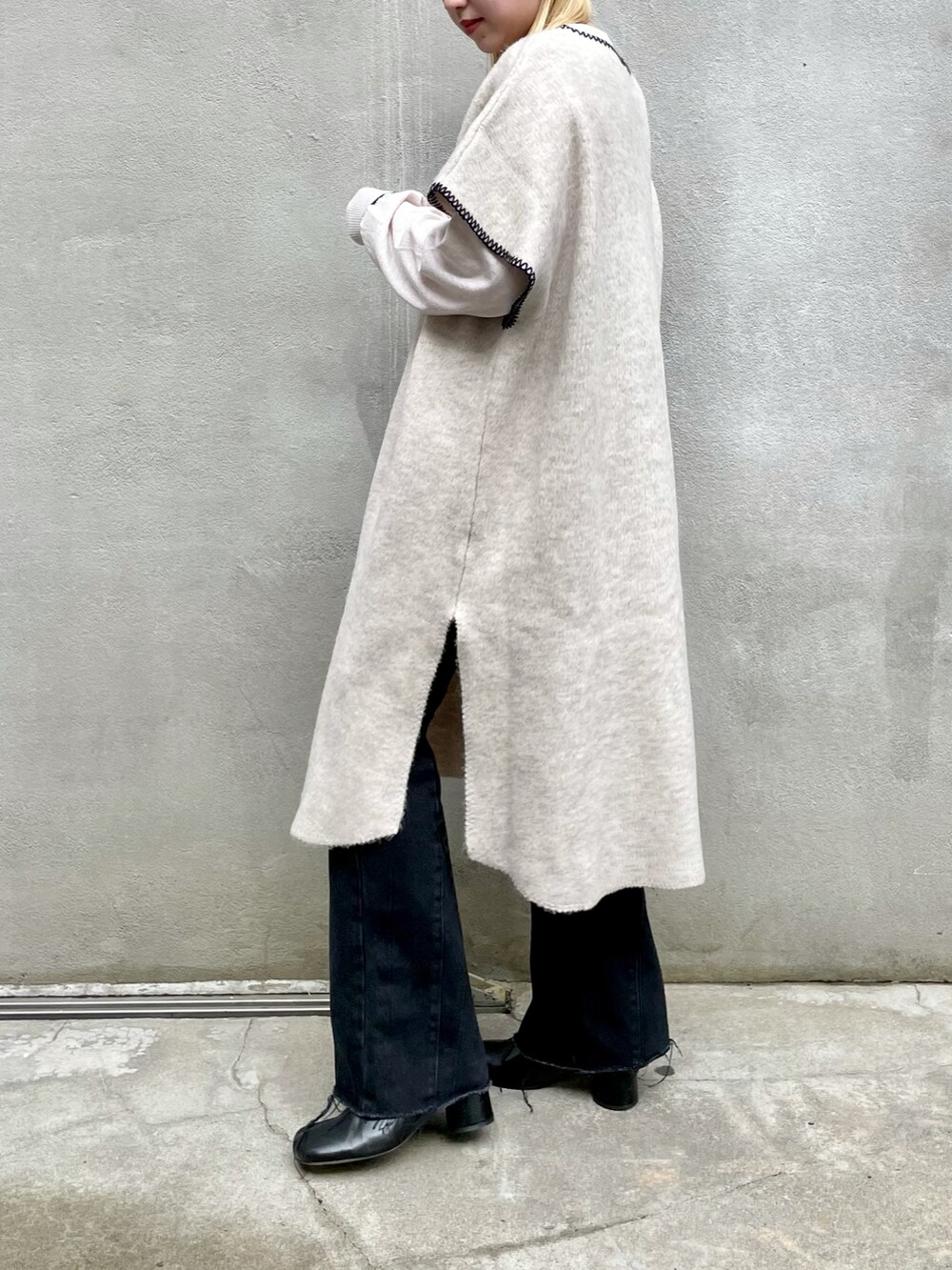 ホワイト系のニット/セーター、ブラック系のデニムパンツ、ブラック系のブーツを着用したレディースの秋コーディネートの3枚目の写真