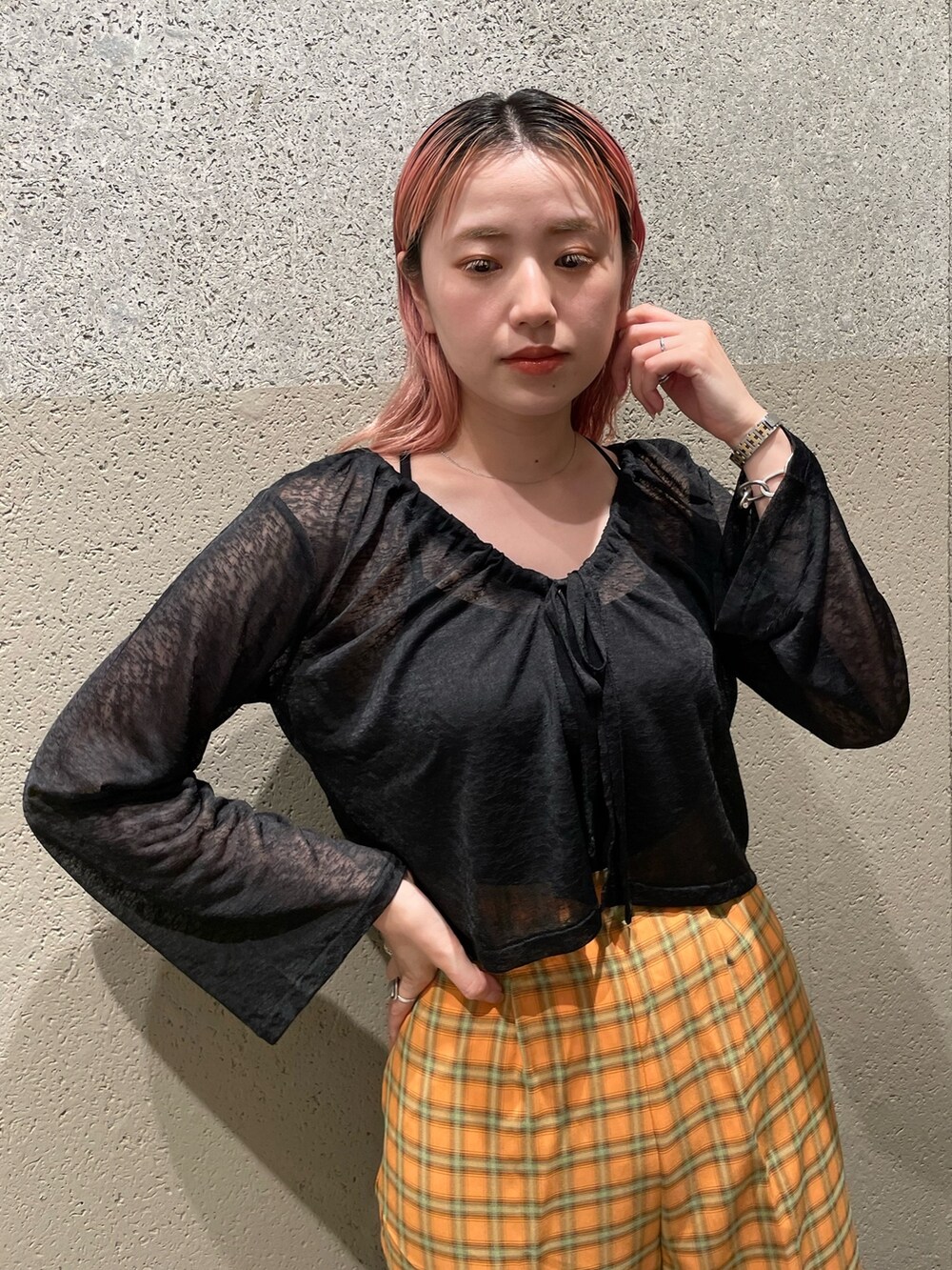 ブラック系のカーディガン/ボレロ、オレンジ系のスラックスを着用したレディースの夏コーディネートの3枚目の写真