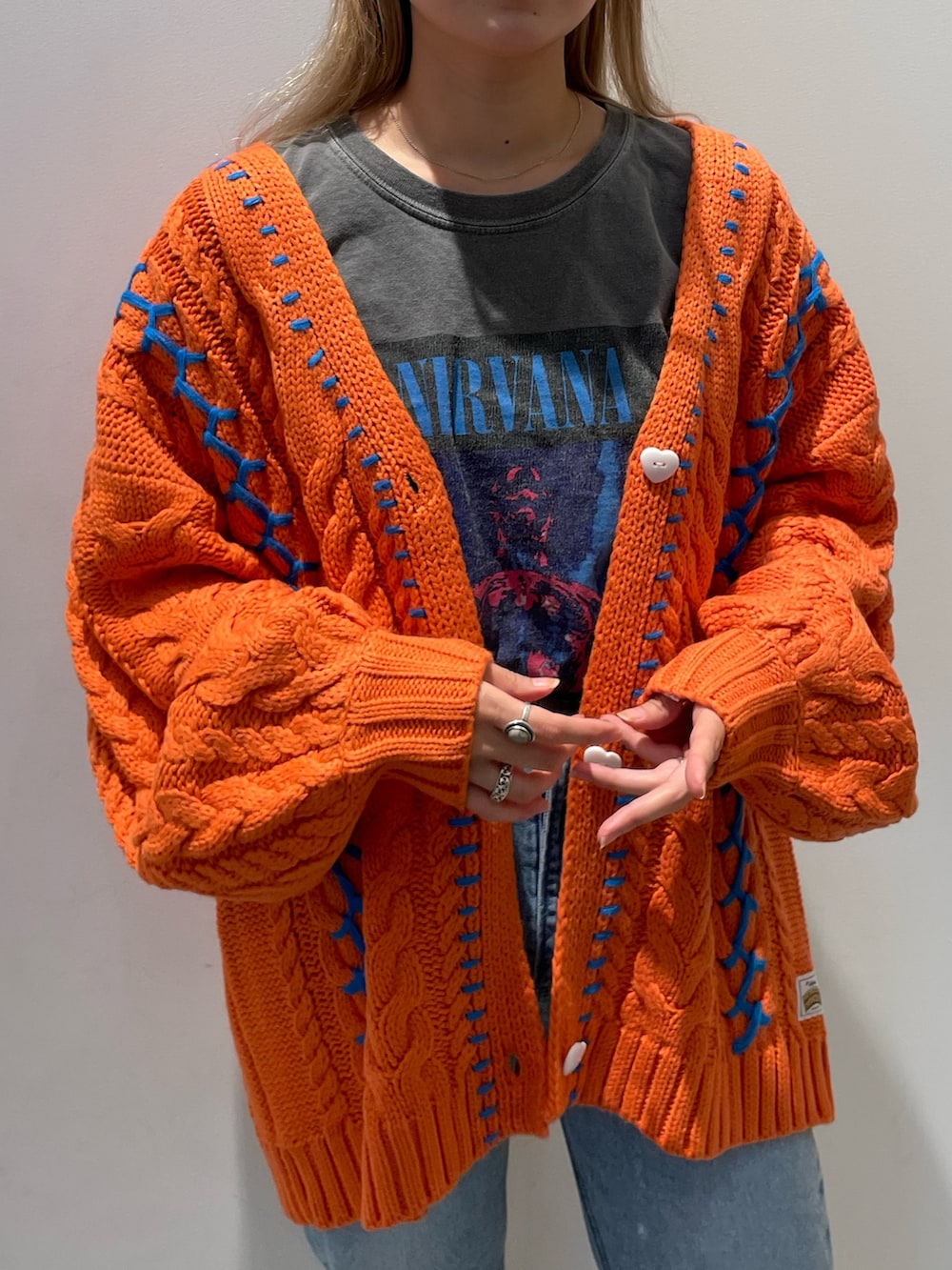 オレンジ系のカーディガン/ボレロ、ブルー系のデニムパンツ、ベージュ系のトートバッグを着用したレディースの秋コーディネートの2枚目の写真