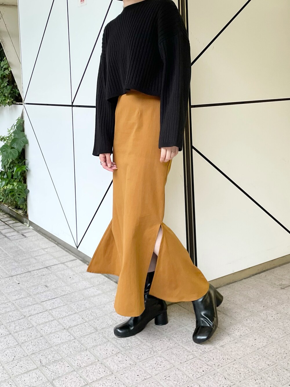 ブラック系のニット/セーター、イエロー系のスカート、ブラック系のブーツを着用したレディースの秋コーディネートの4枚目の写真