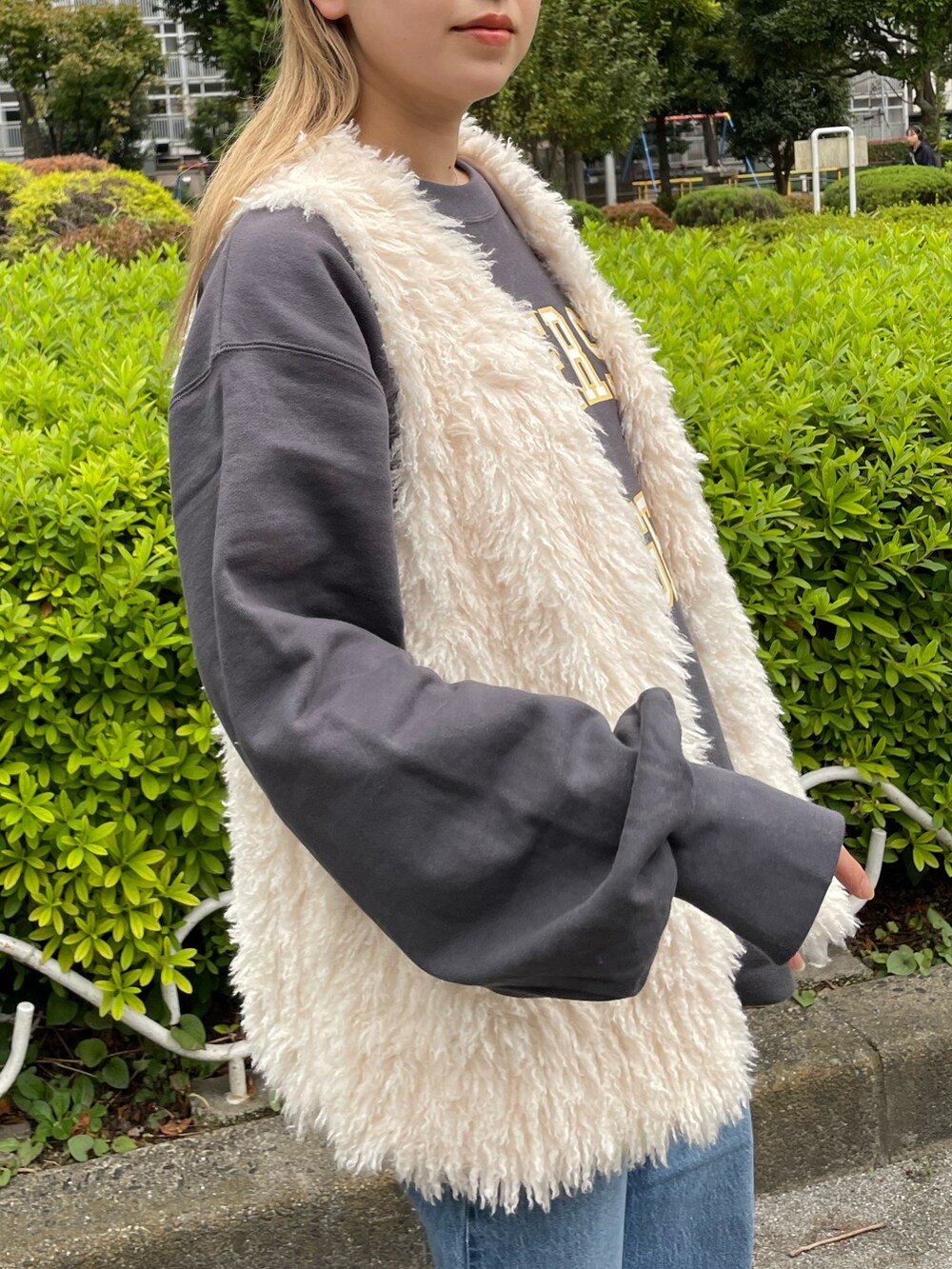 ホワイト系のベスト、グレー系のスウェット、ブルー系のデニムパンツを着用したレディースの秋コーディネートの5枚目の写真