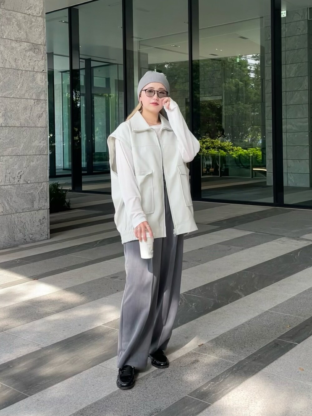 ホワイト系のジャケット/アウター、ホワイト系のTシャツ/カットソー、グレー系のスラックスを着用したレディースの秋コーディネートの2枚目の写真