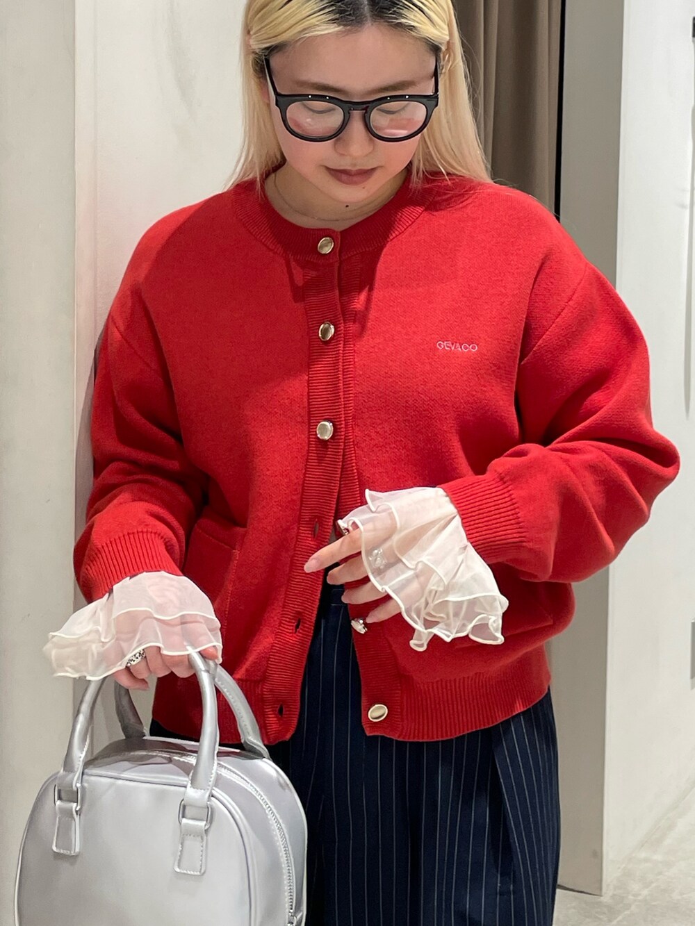 レッド系のカーディガン/ボレロ、イエロー系のTシャツ/カットソー、ブルー系のスラックスを着用したレディースの冬コーディネートの4枚目の写真