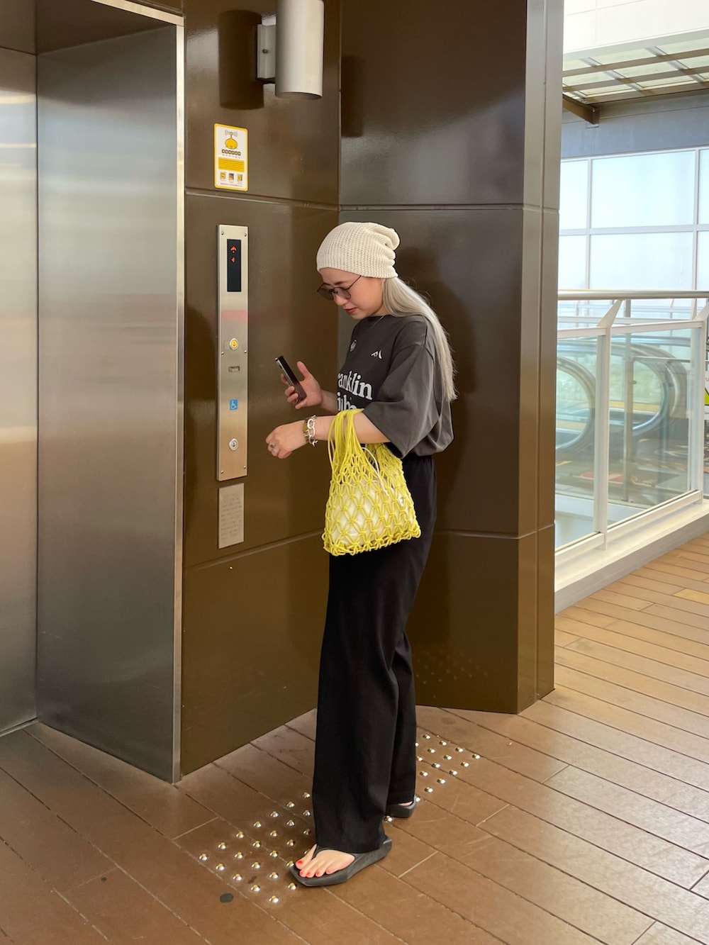 グレー系のTシャツ/カットソー、イエロー系のバッグ、ホワイト系のニットキャップ/ビーニーを着用したレディースの夏コーディネートの5枚目の写真