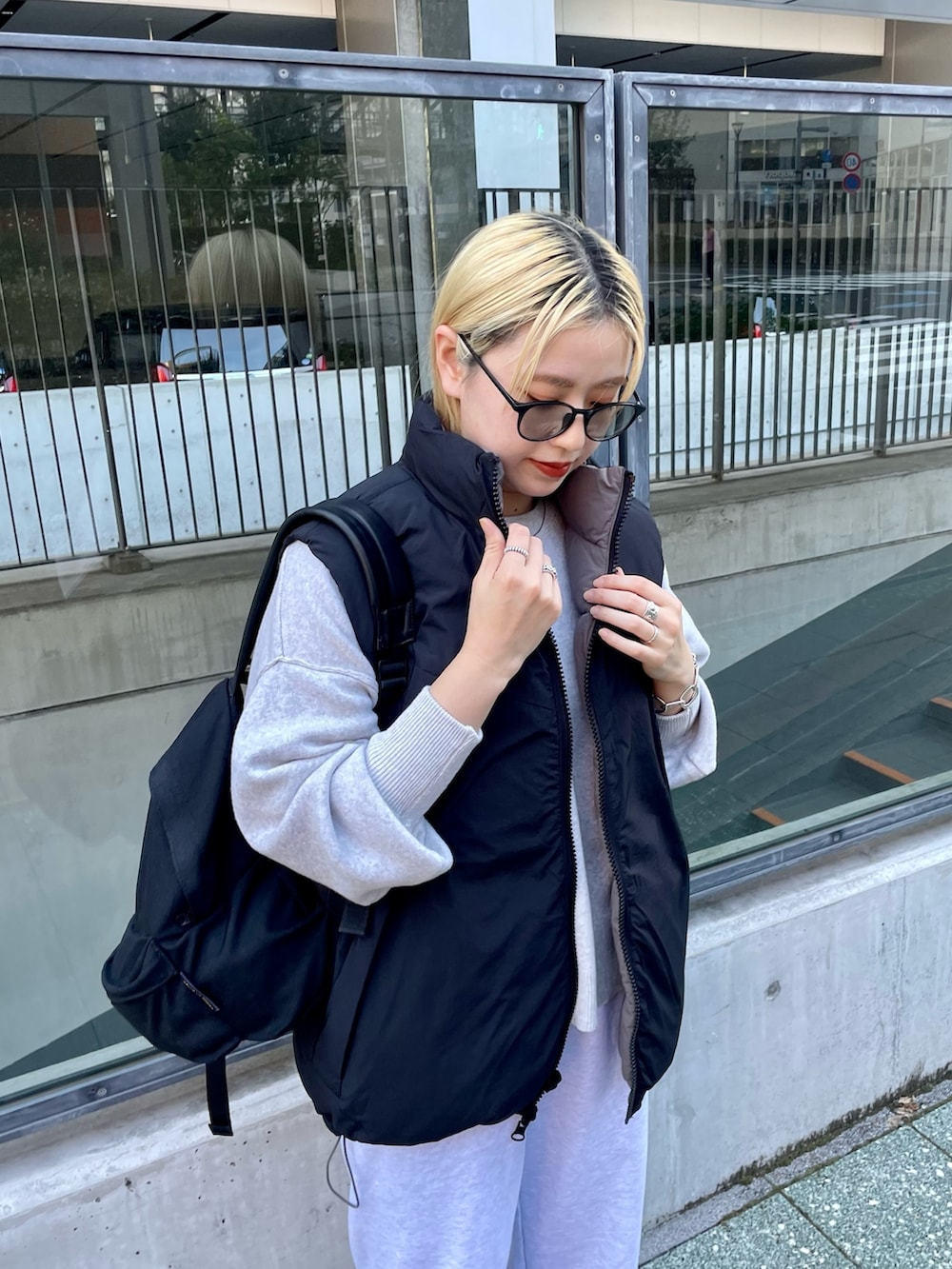 ブラック系のダウンベスト、ホワイト系のニット/セーター、グレー系のスウェットパンツを着用したレディースの冬コーディネートの5枚目の写真