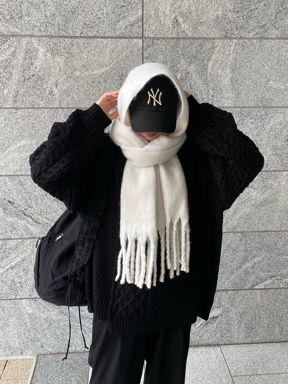 ブラック系のショルダーバッグ、ブラック系のニット/セーター、ホワイト系のマフラーを着用したレディースの冬コーディネートの4枚目の写真