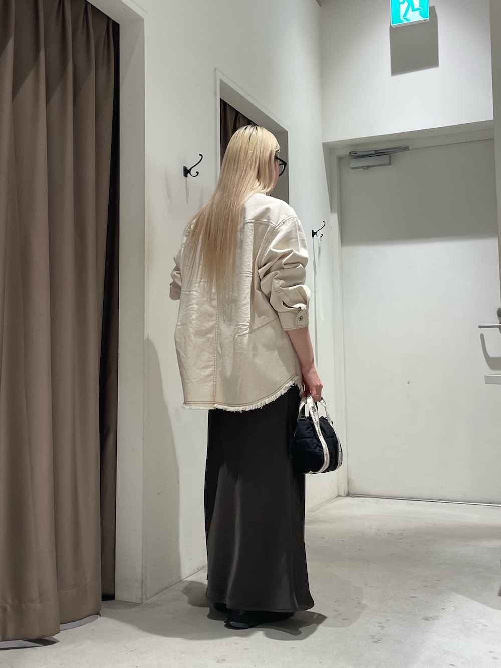 ホワイト系のデニムジャケット、グレー系のスカートを着用したレディースの春コーディネートの3枚目の写真