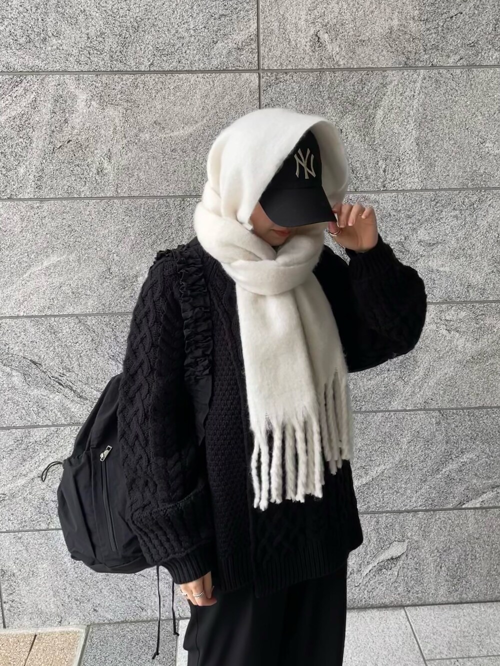 ブラック系のショルダーバッグ、ブラック系のニット/セーター、ホワイト系のマフラーを着用したレディースの冬コーディネートの5枚目の写真