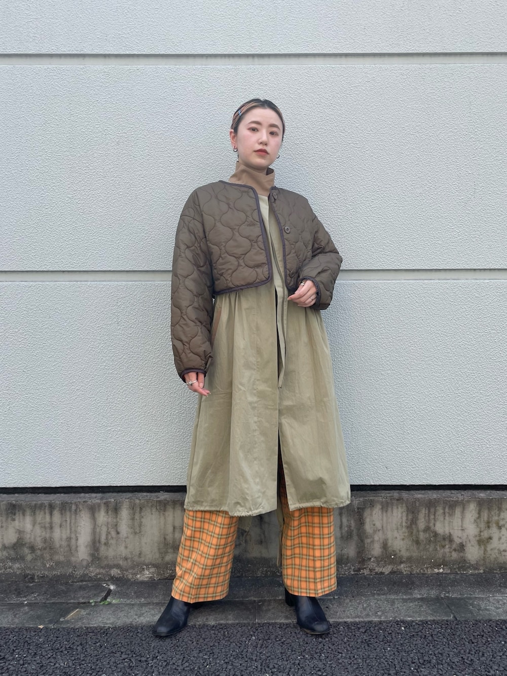 グリーン系のノーカラーコート、オレンジ系のスラックスを着用したレディースの夏コーディネートの3枚目の写真