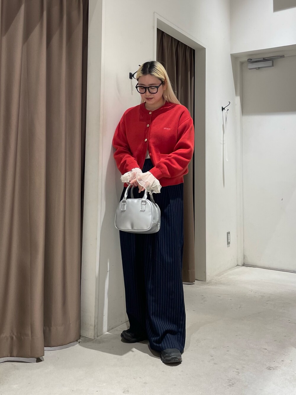 レッド系のカーディガン/ボレロ、イエロー系のTシャツ/カットソー、ブルー系のスラックスを着用したレディースの冬コーディネートの3枚目の写真