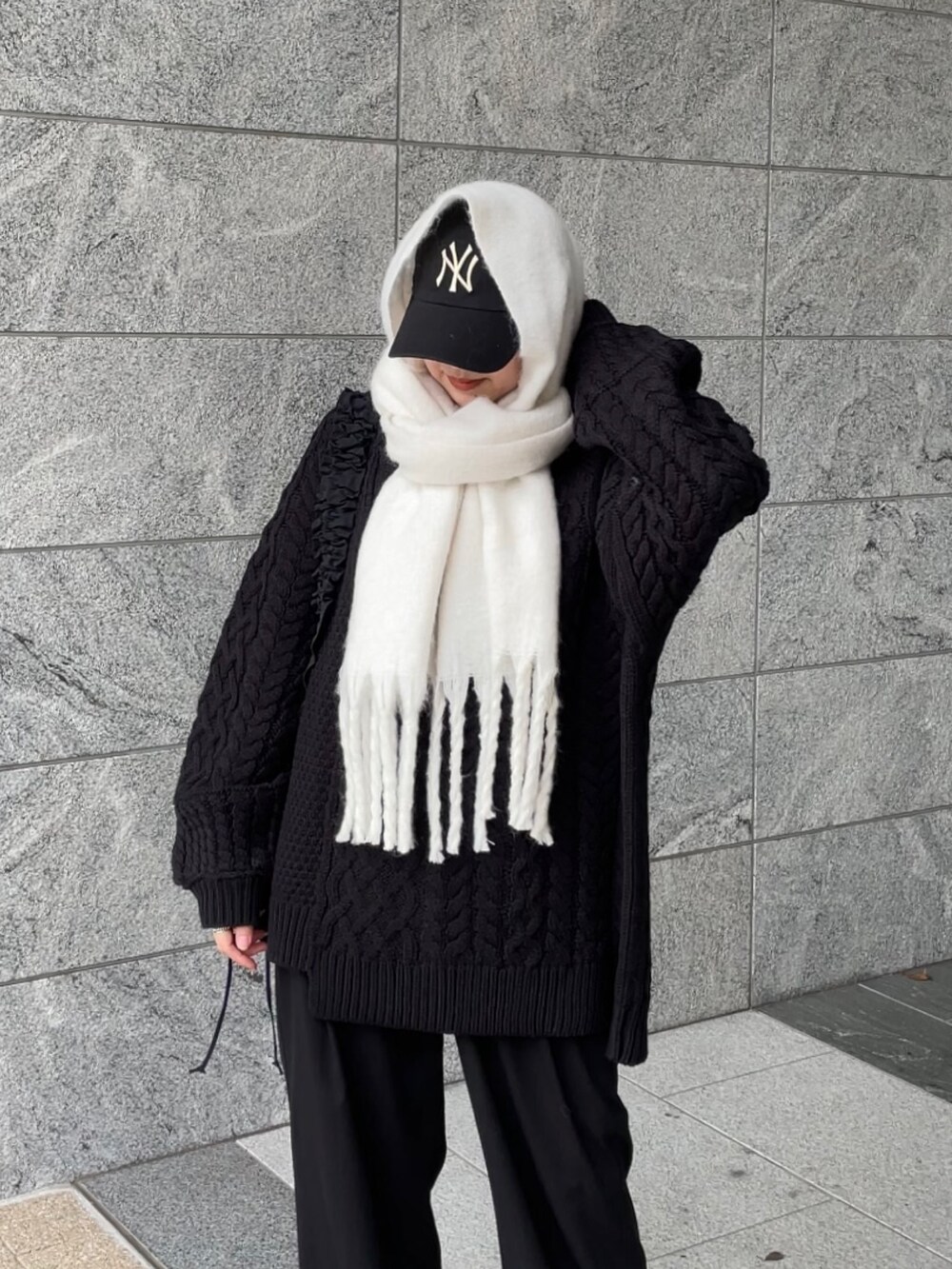 ブラック系のショルダーバッグ、ブラック系のニット/セーター、ホワイト系のマフラーを着用したレディースの冬コーディネートの8枚目の写真