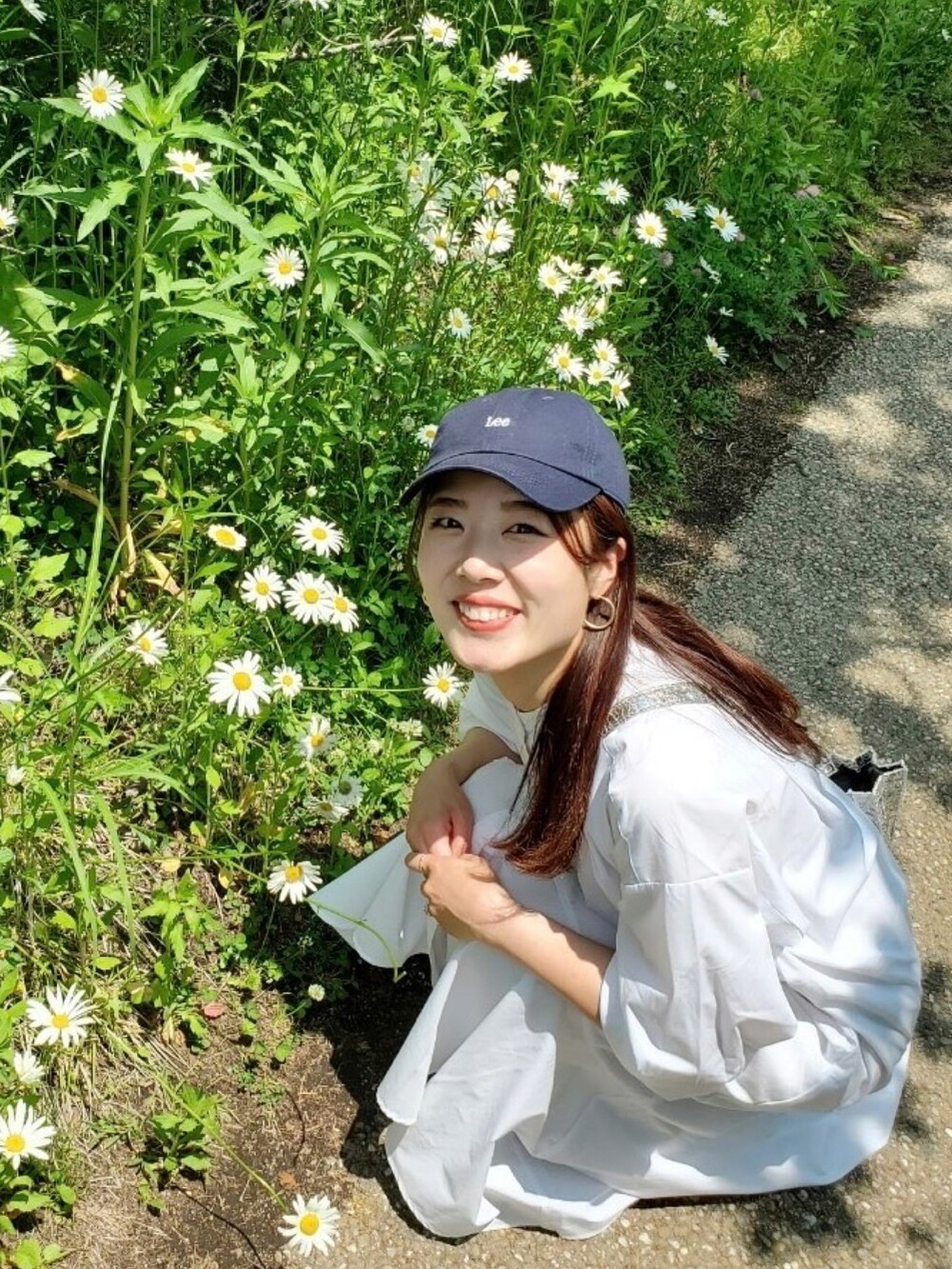 ホワイト系のシャツワンピース、シルバー系のハンドバッグ、ベージュ系のスニーカーを着用したレディースの夏コーディネートの2枚目の写真