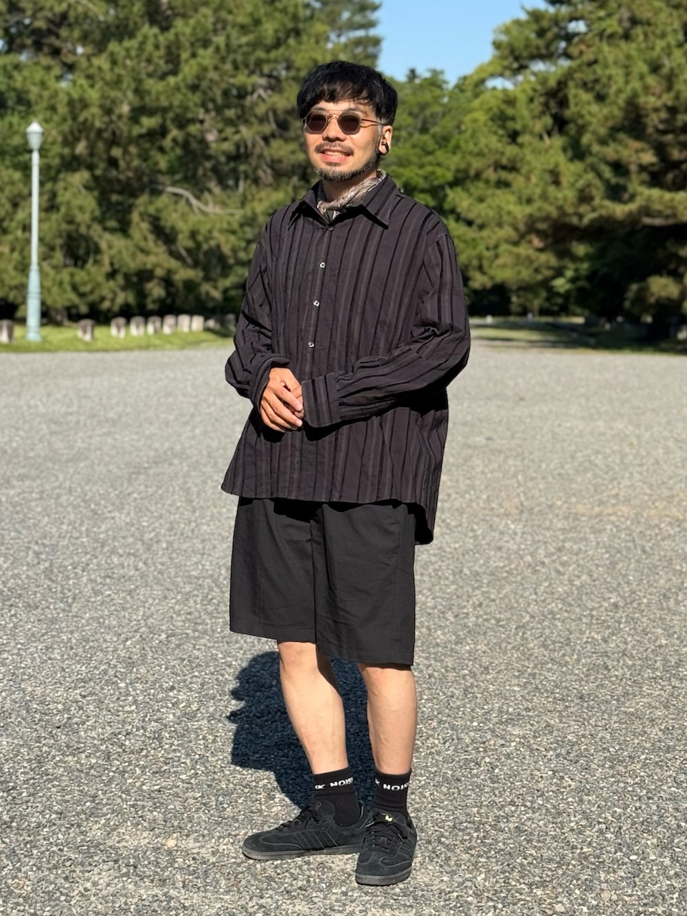 ブラック系のスニーカー、ブラック系のパンツを着用したメンズの夏コーディネートの4枚目の写真