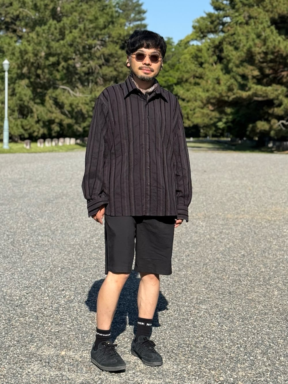 ブラック系のスニーカー、ブラック系のパンツを着用したメンズの夏コーディネートの3枚目の写真