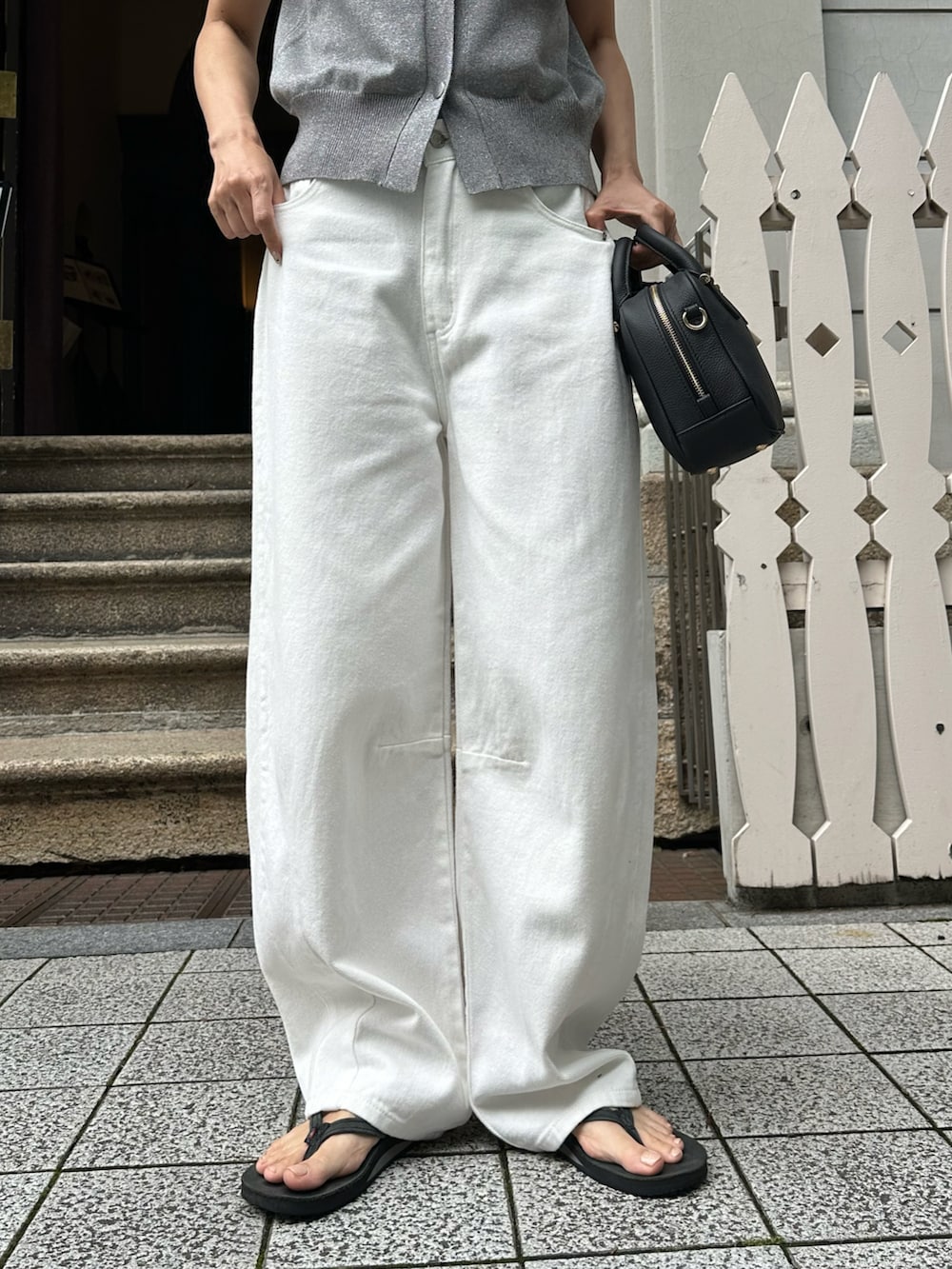 シルバー系のベスト、ホワイト系のデニムパンツ、ブラック系のバッグを着用したレディースの夏コーディネートの4枚目の写真