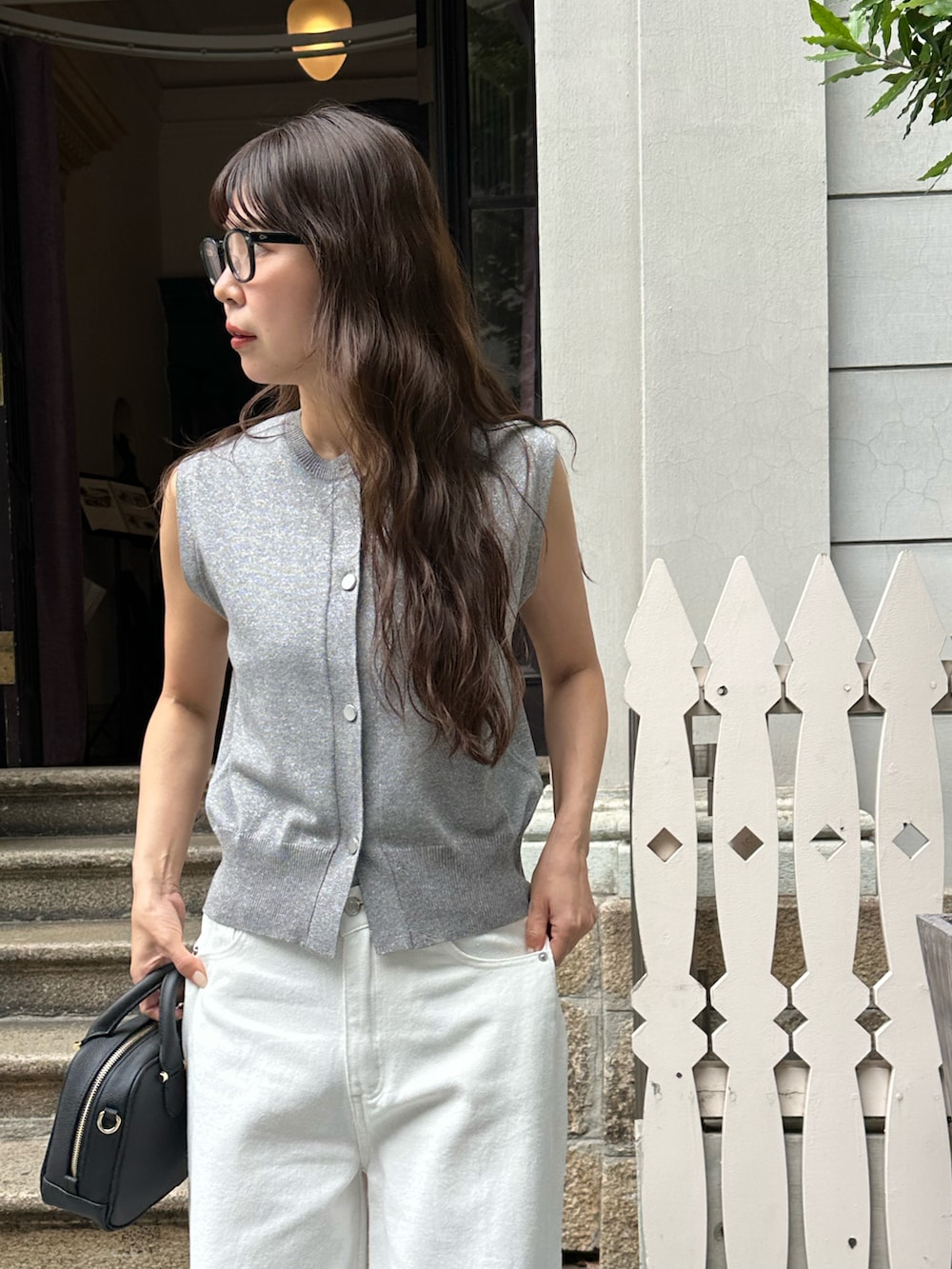 シルバー系のベスト、ホワイト系のデニムパンツ、ブラック系のバッグを着用したレディースの夏コーディネートの3枚目の写真
