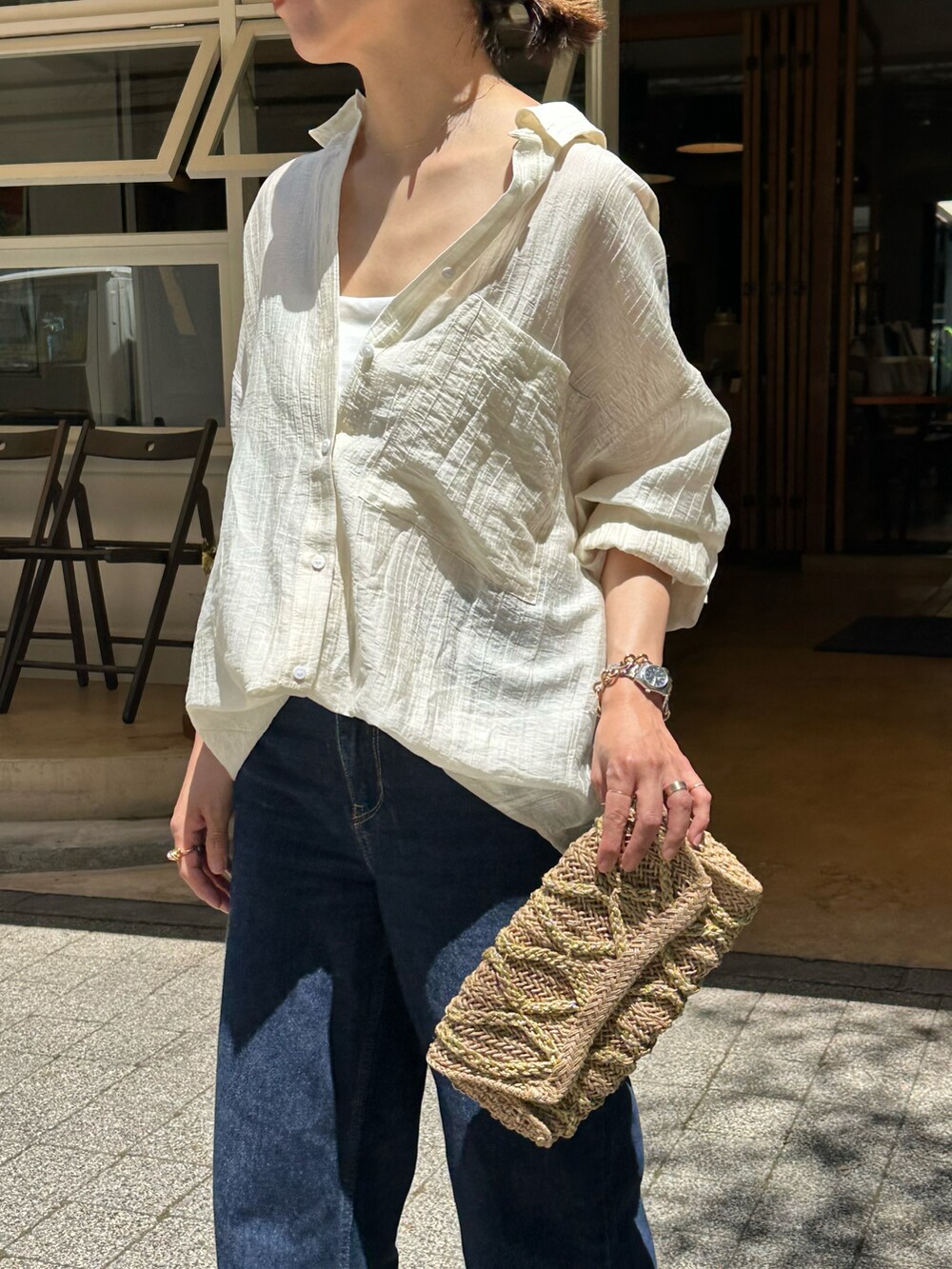 ブルー系のデニムパンツ、ホワイト系のシャツ/ブラウス、ベージュ系のクラッチバッグを着用したレディースの春コーディネートの3枚目の写真
