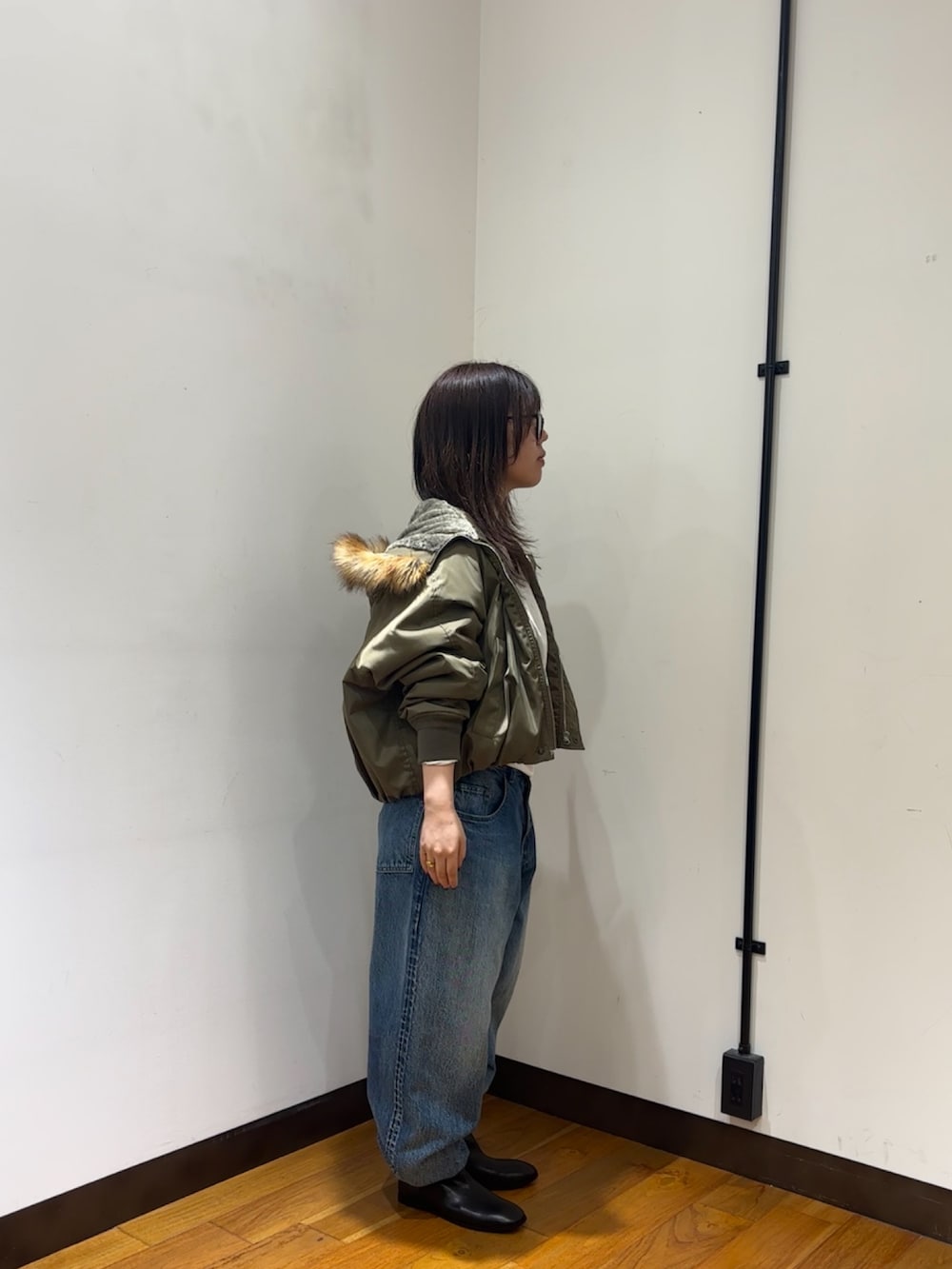 ホワイト系のTシャツ/カットソー、ブラウン系のダウンジャケット/コート、ブルー系のデニムパンツを着用したレディースの秋コーディネートの2枚目の写真