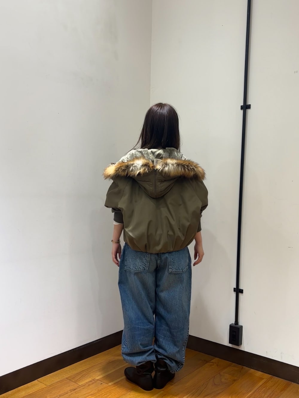 ホワイト系のTシャツ/カットソー、ブラウン系のダウンジャケット/コート、ブルー系のデニムパンツを着用したレディースの秋コーディネートの3枚目の写真