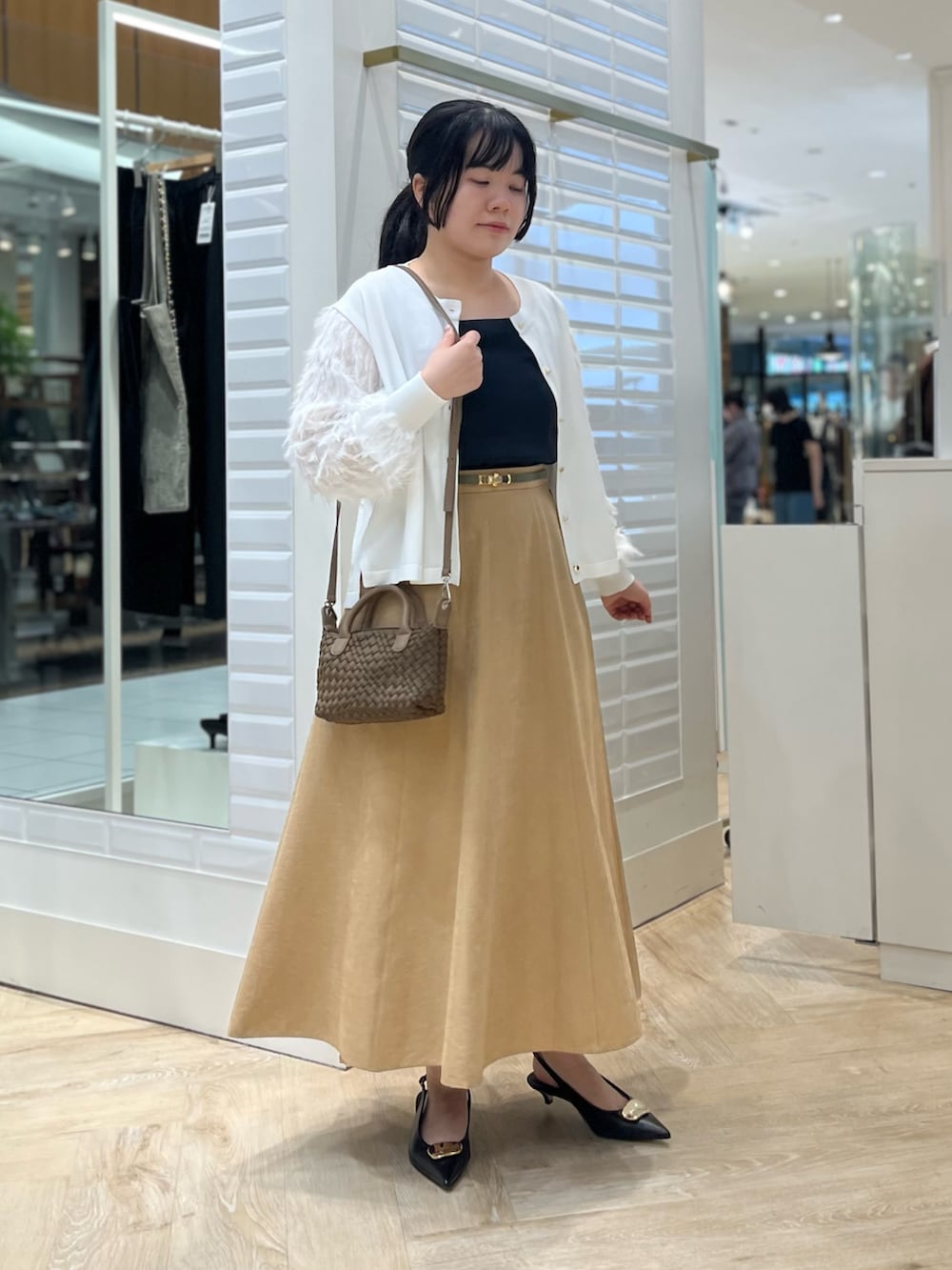 ベージュ系のスカート、ホワイト系のカーディガン/ボレロ、ブラウン系のショルダーバッグを着用したレディースの秋コーディネートの2枚目の写真