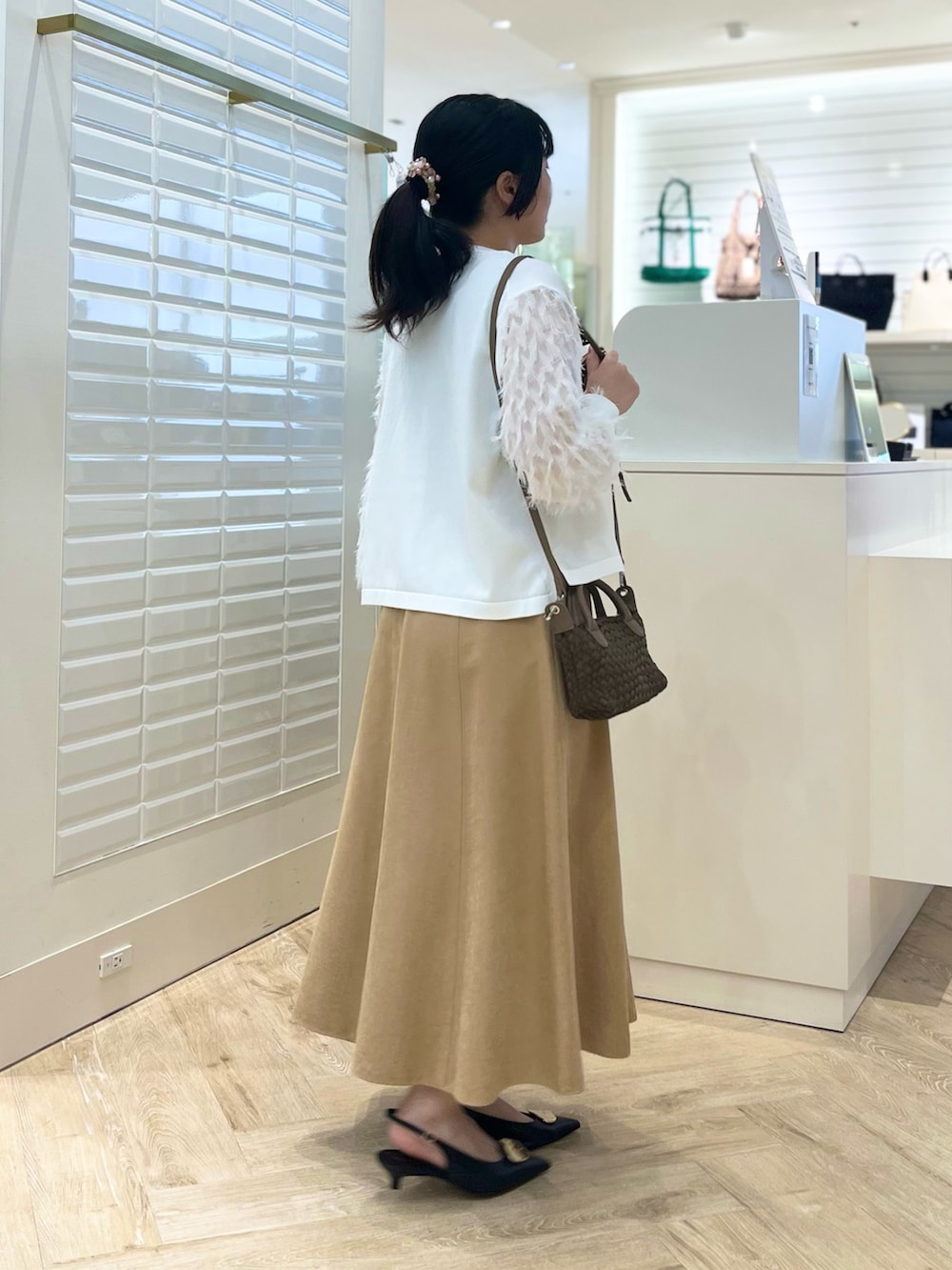 ベージュ系のスカート、ホワイト系のカーディガン/ボレロ、ブラウン系のショルダーバッグを着用したレディースの秋コーディネートの4枚目の写真