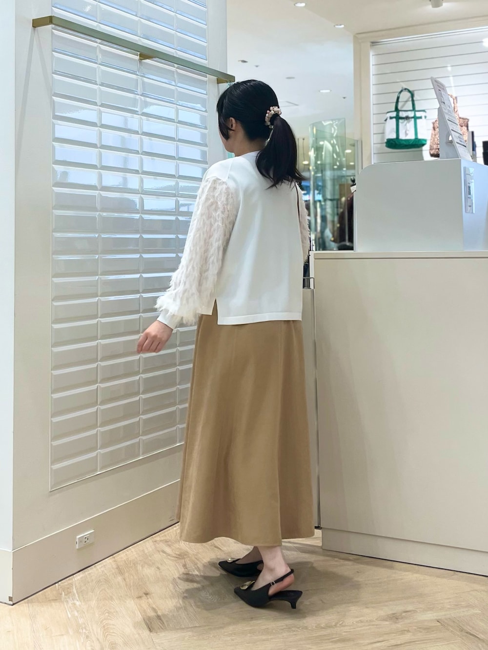 ベージュ系のスカート、ホワイト系のカーディガン/ボレロ、ブラウン系のショルダーバッグを着用したレディースの秋コーディネートの6枚目の写真