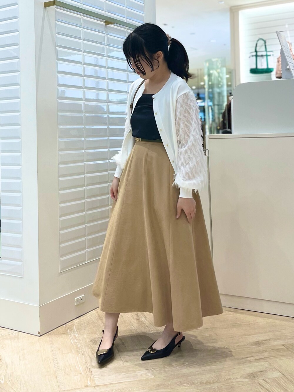 ベージュ系のスカート、ホワイト系のカーディガン/ボレロ、ブラウン系のショルダーバッグを着用したレディースの秋コーディネートの10枚目の写真