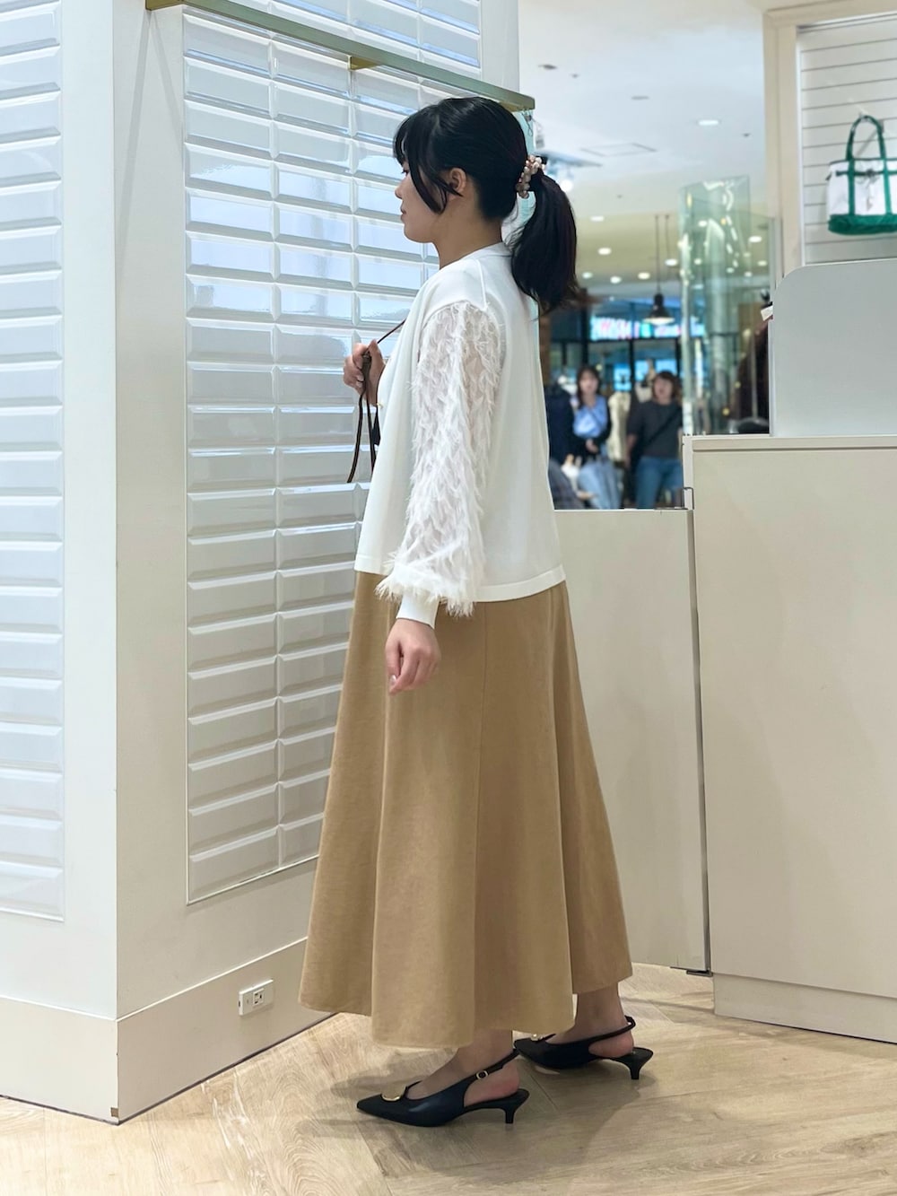 ベージュ系のスカート、ホワイト系のカーディガン/ボレロ、ブラウン系のショルダーバッグを着用したレディースの秋コーディネートの7枚目の写真