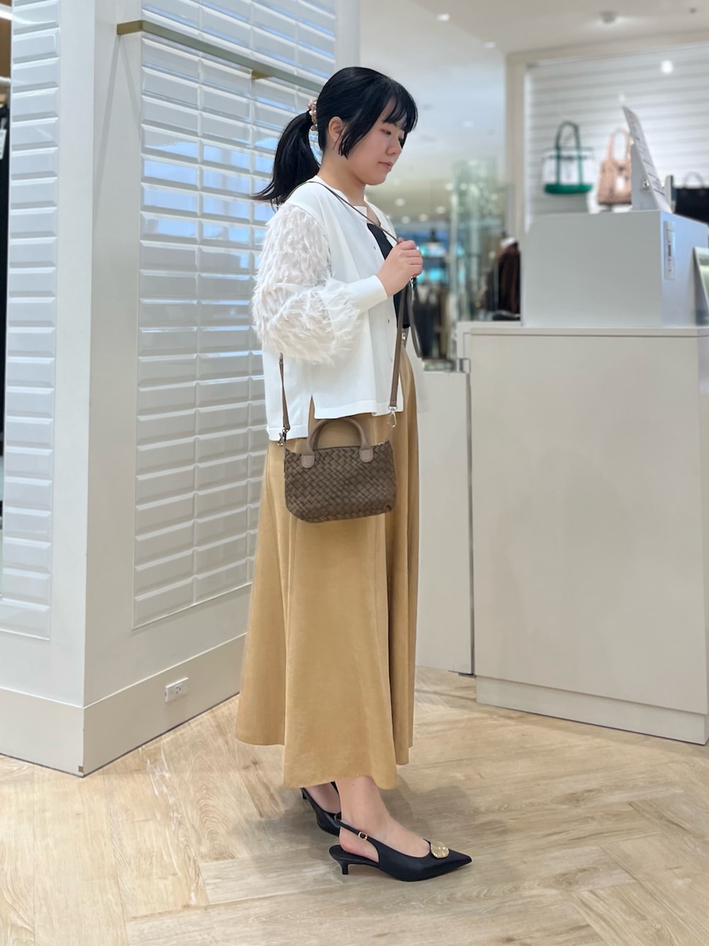 ベージュ系のスカート、ホワイト系のカーディガン/ボレロ、ブラウン系のショルダーバッグを着用したレディースの秋コーディネートの3枚目の写真