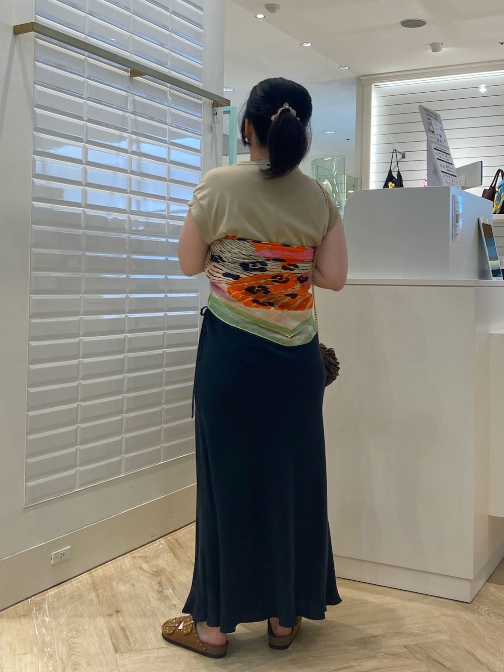 ベージュ系のTシャツ/カットソー、ブラック系のスカート、イエロー系のサンダルを着用したレディースの夏コーディネートの4枚目の写真