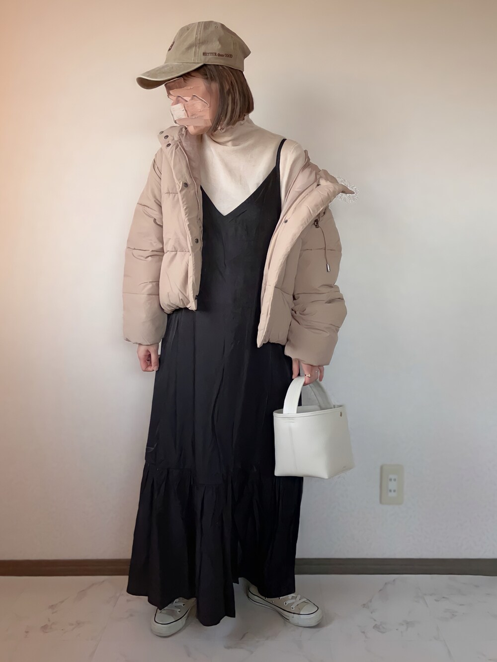 ベージュ系のダウンジャケット/コート、ブラック系のワンピース、ベージュ系のTシャツ/カットソーを着用したレディースの秋コーディネートの2枚目の写真